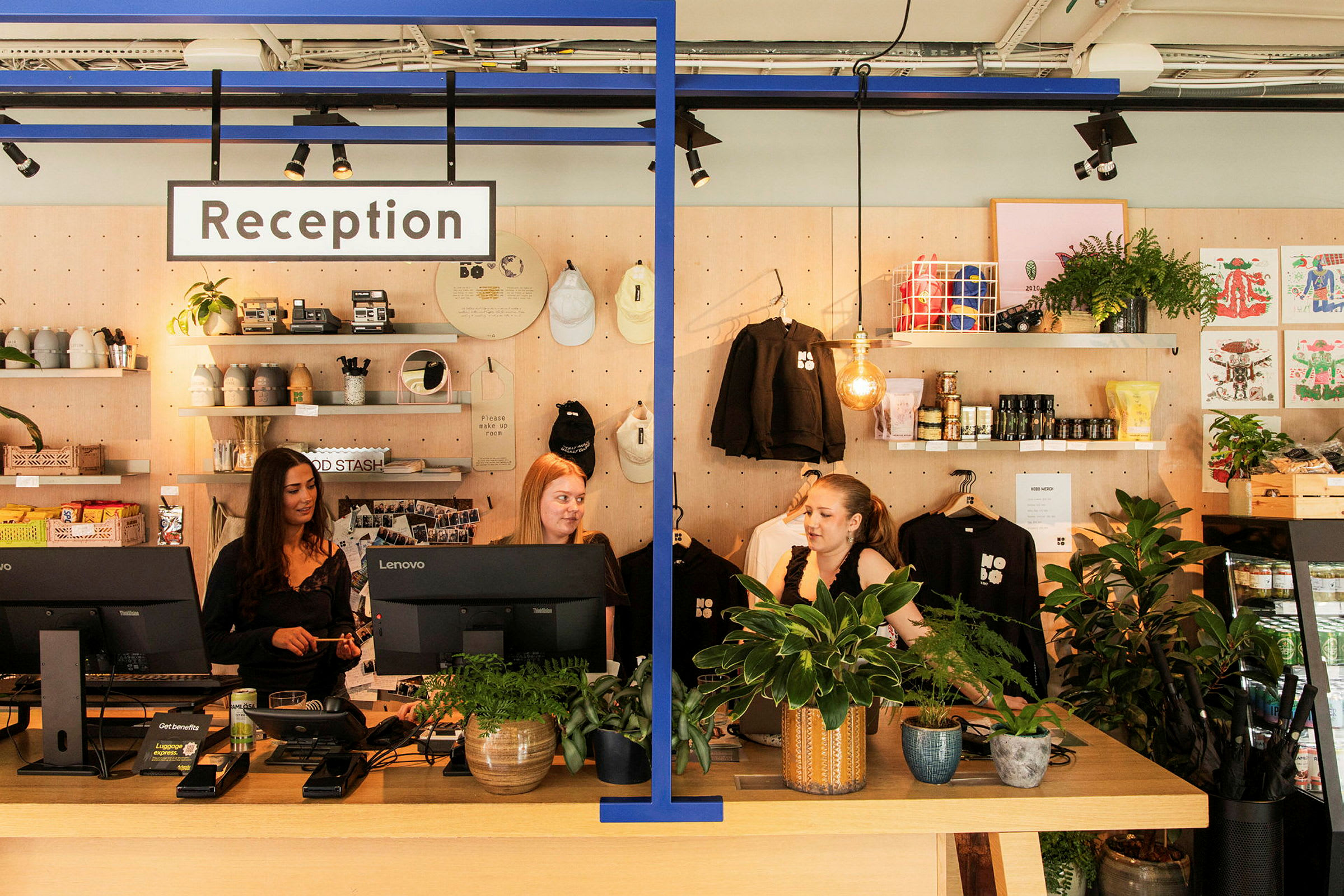 Receptionen med medarbejdere bag en receptionsdisk, planter og dekorative genstande på hylderne i baggrunden. (AI-genereret tekst)