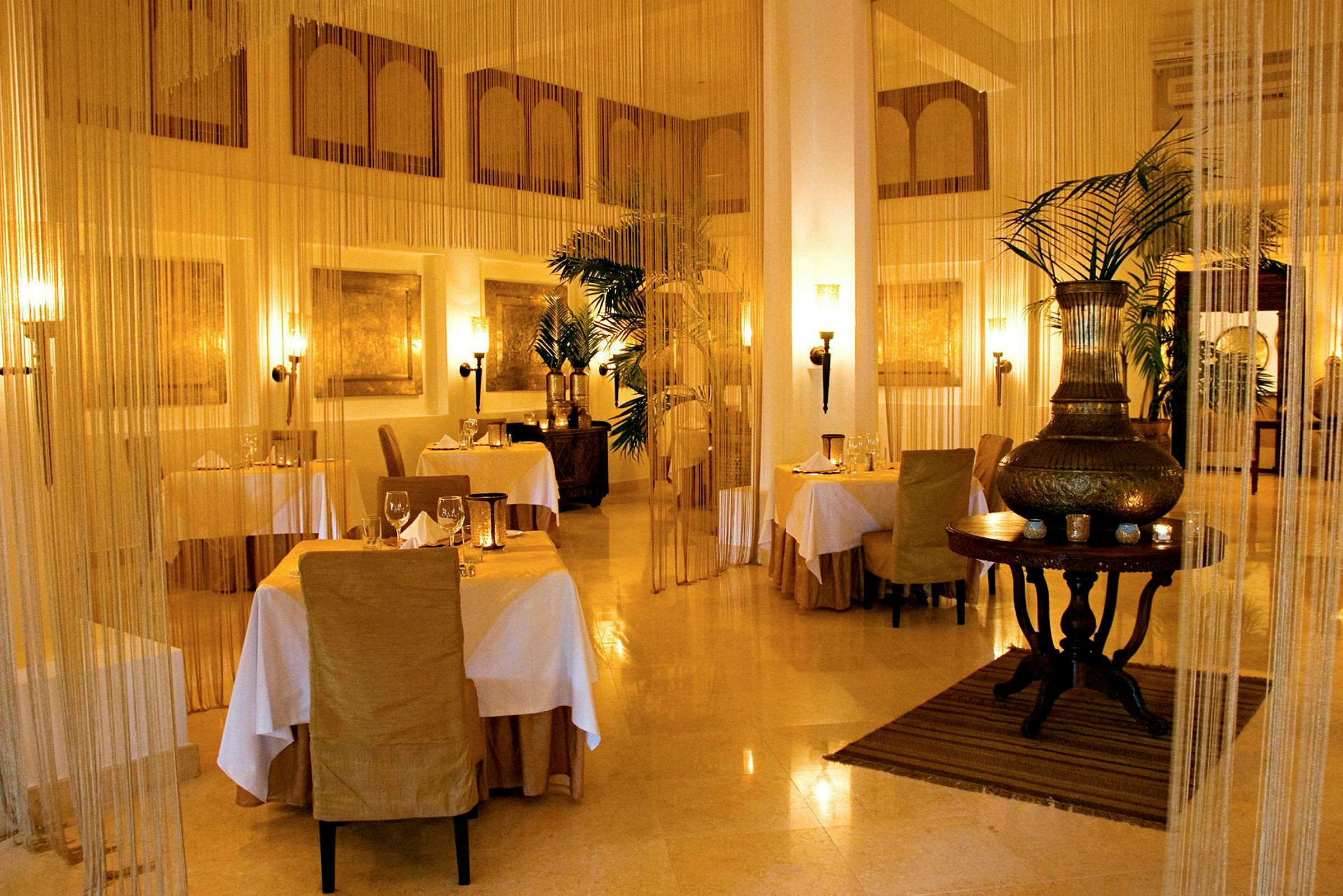 En elegant restaurant med dækkede borde, stole betrukket i beige og blød belysning. (AI-genereret tekst)