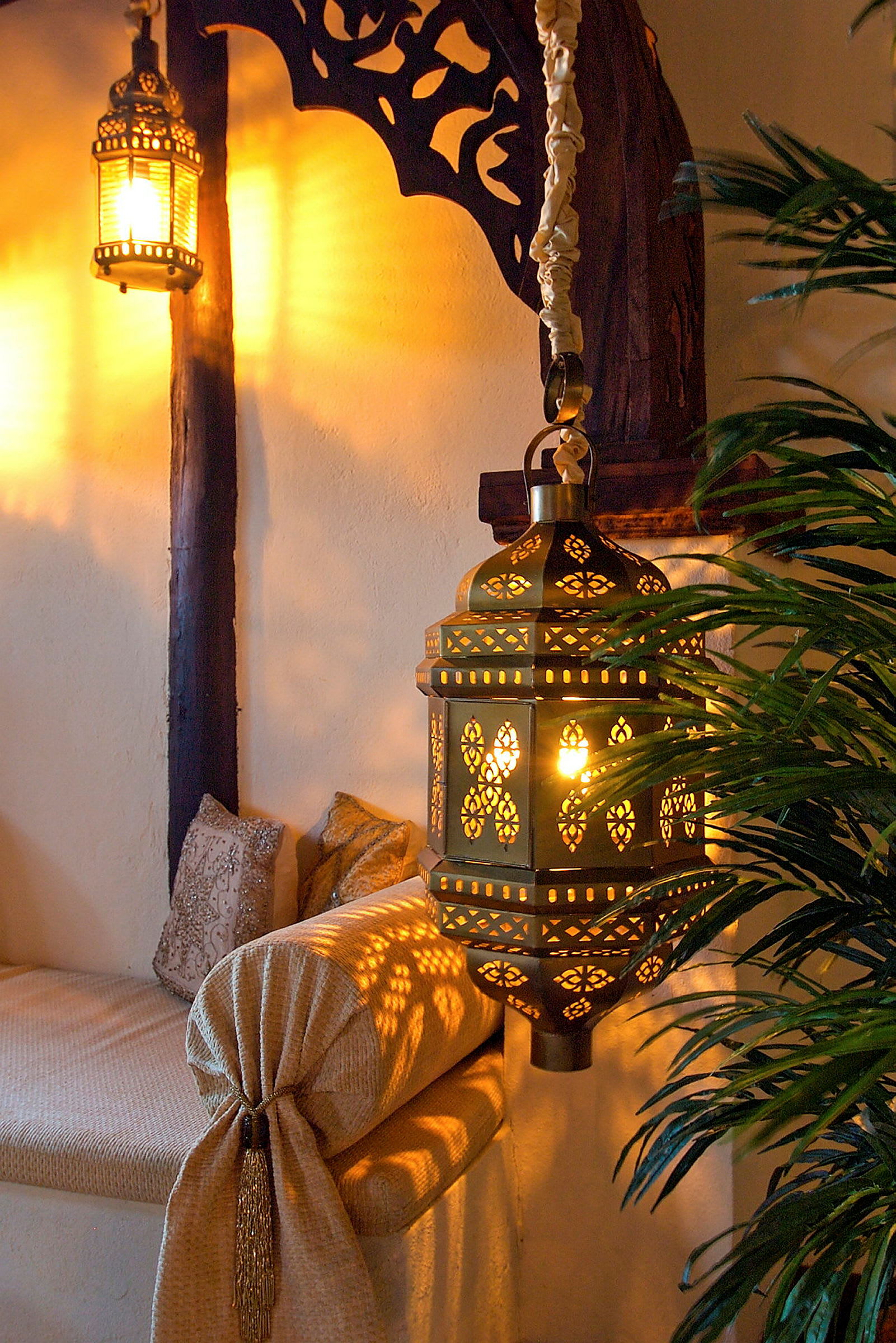 En oplyst orientalsk inspireret lampe hænger i interiør med dekorative detaljer og betræk. (AI-genereret tekst)
