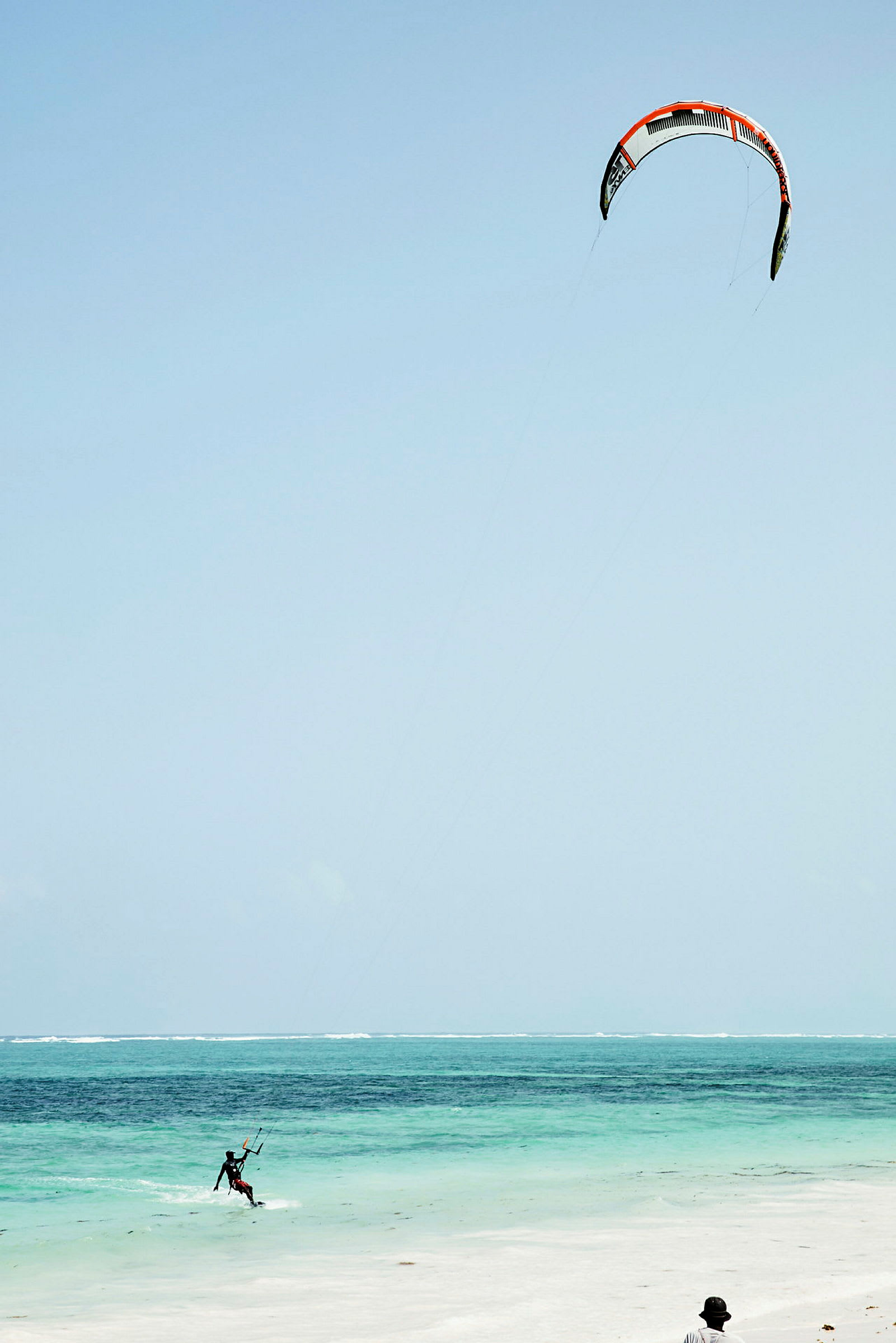 En person kitesurfer på en klarblå havstrand. (AI-genereret tekst)