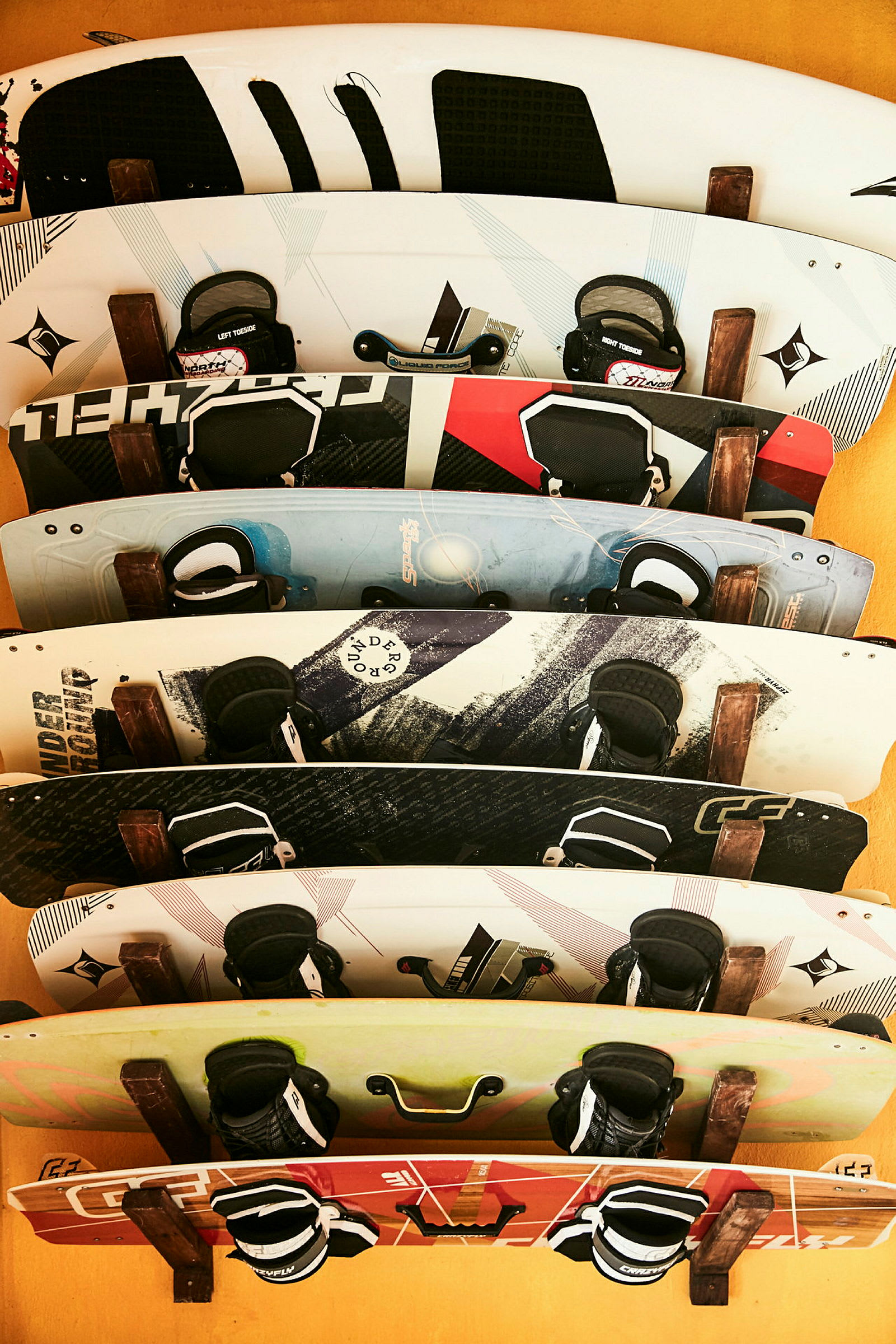 Flere wakeboards opstillet mod en gul væg. (AI-genereret tekst)