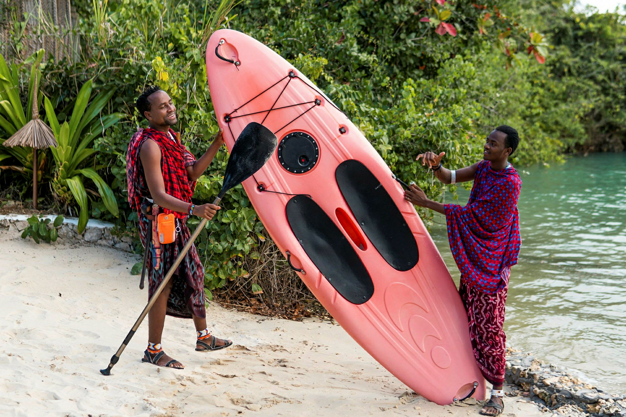 To personer står på en sandstrand med en pink kajak. (AI-genereret tekst)