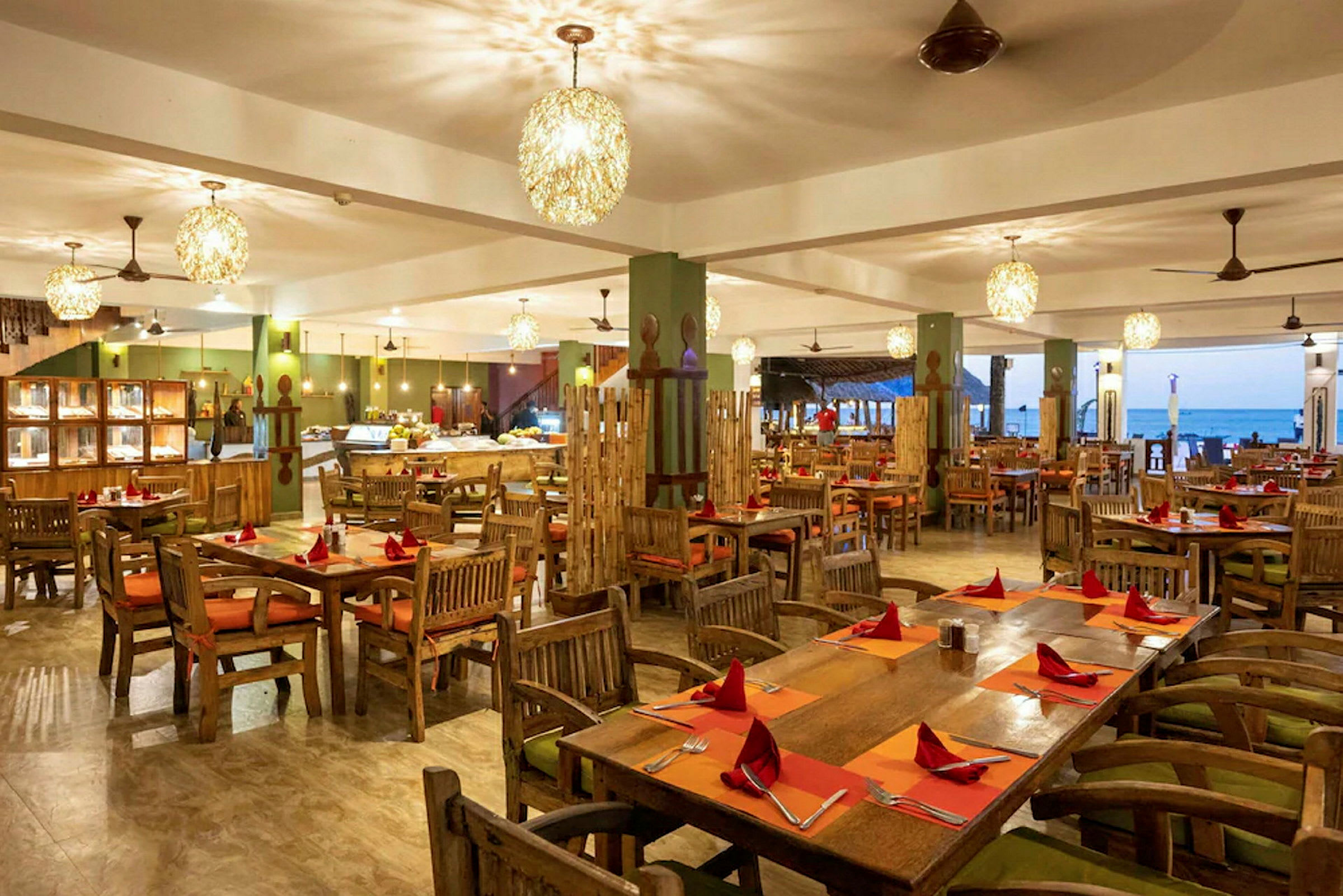 Restaurant med træborde og stole, dækket med orange underlag og røde servietter. (AI-genereret tekst)