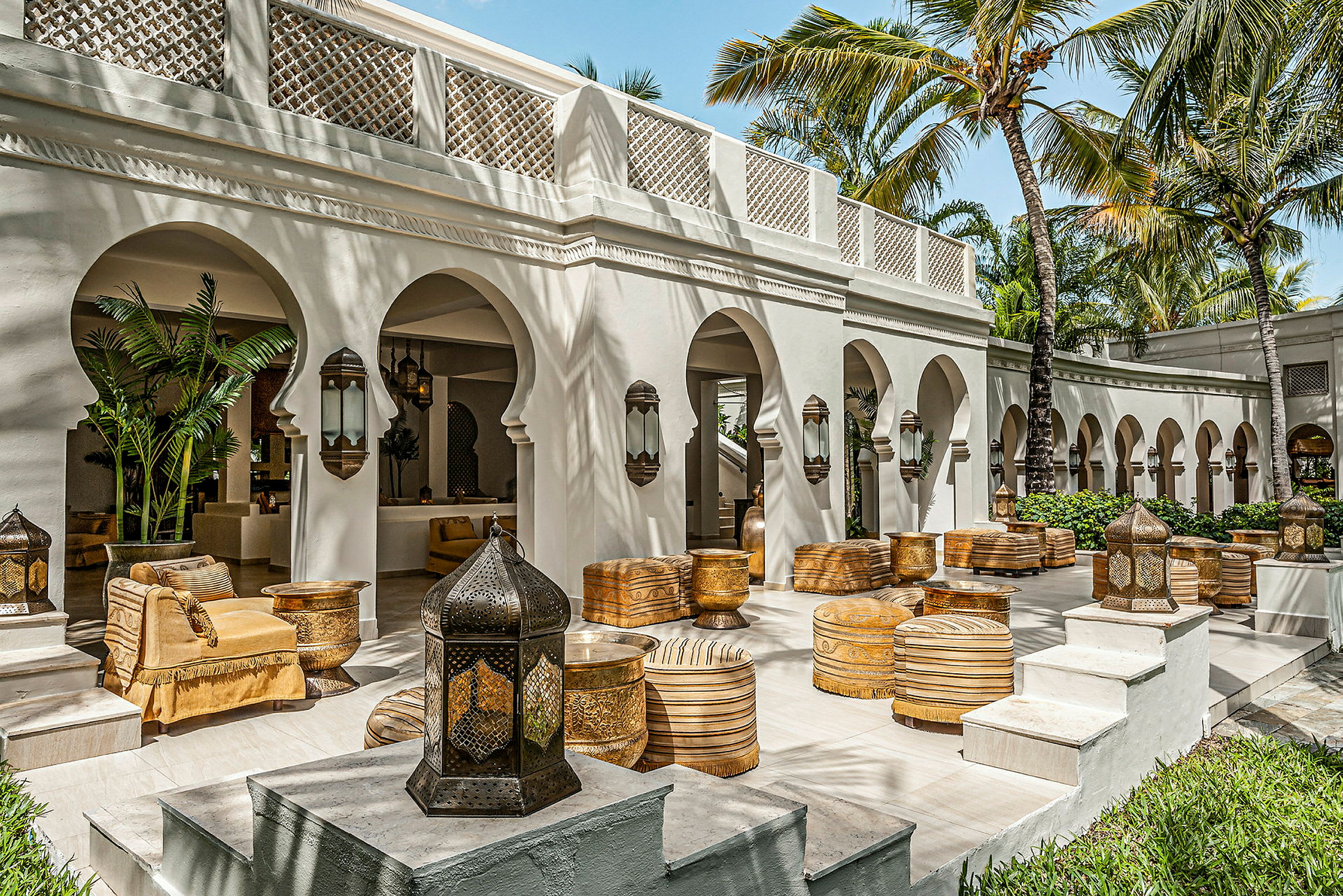 En udendørs terrasse med buer, palmer og siddepladser inspireret af arabisk design. (AI-genereret tekst)