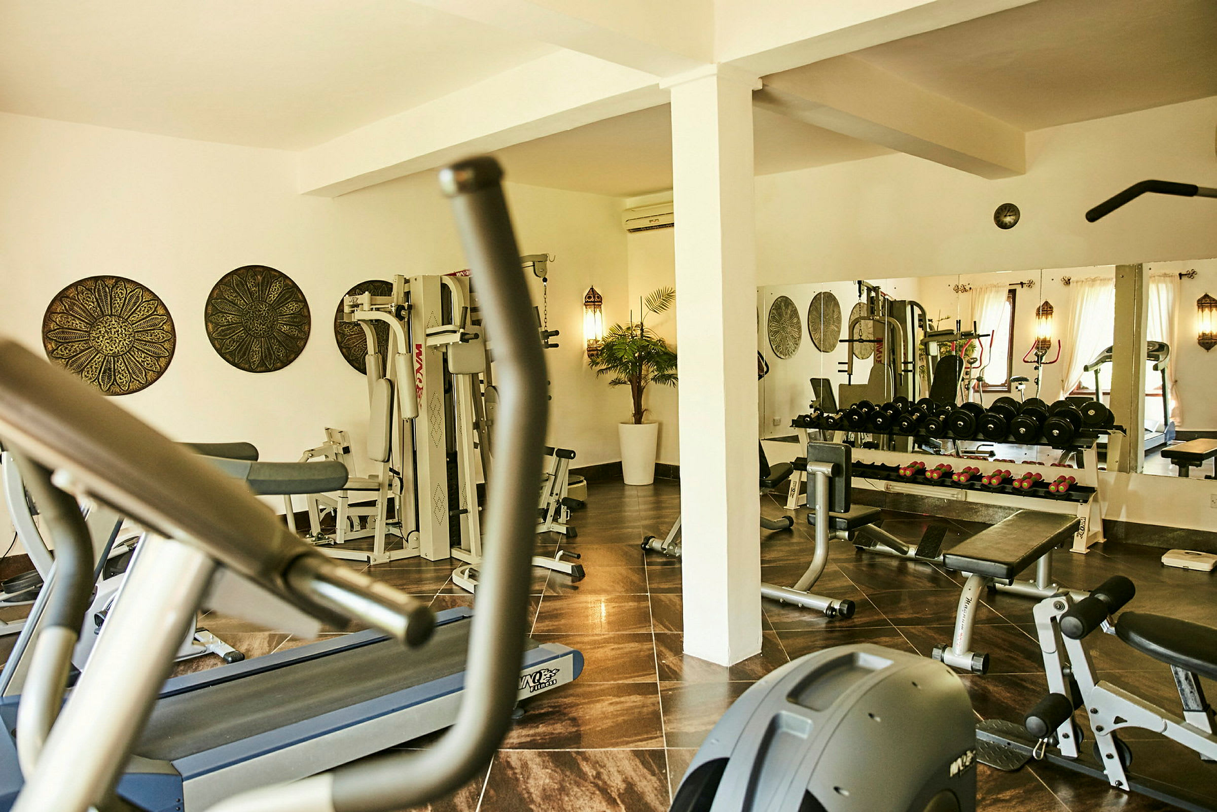 Fitnessrum med træningsudstyr såsom vægte og konditionsmaskiner. (AI-genereret tekst)