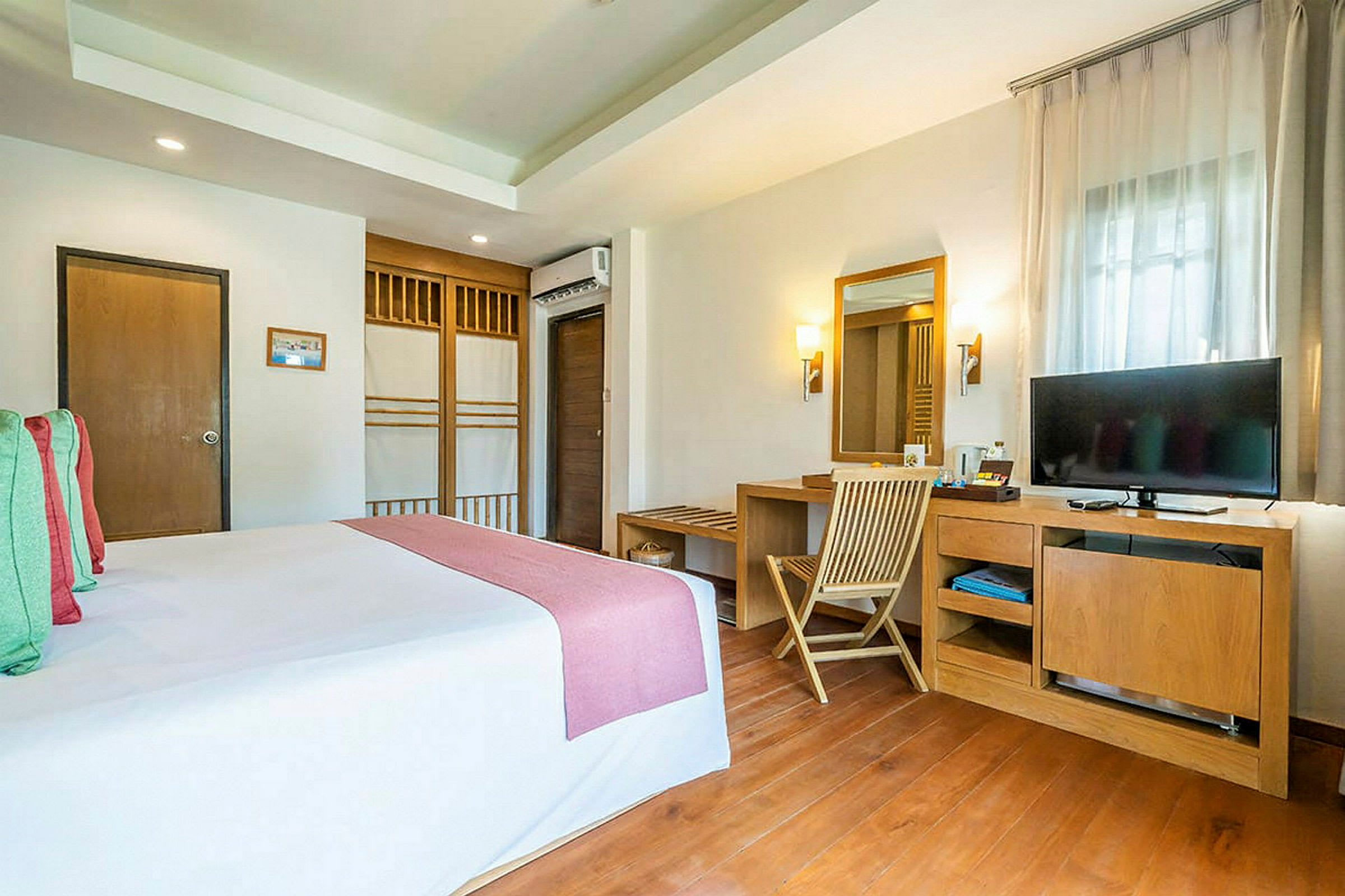 Billede af et hotelværelse med en redt seng og et skrivebord med et spejl og et TV. (AI-genereret tekst)