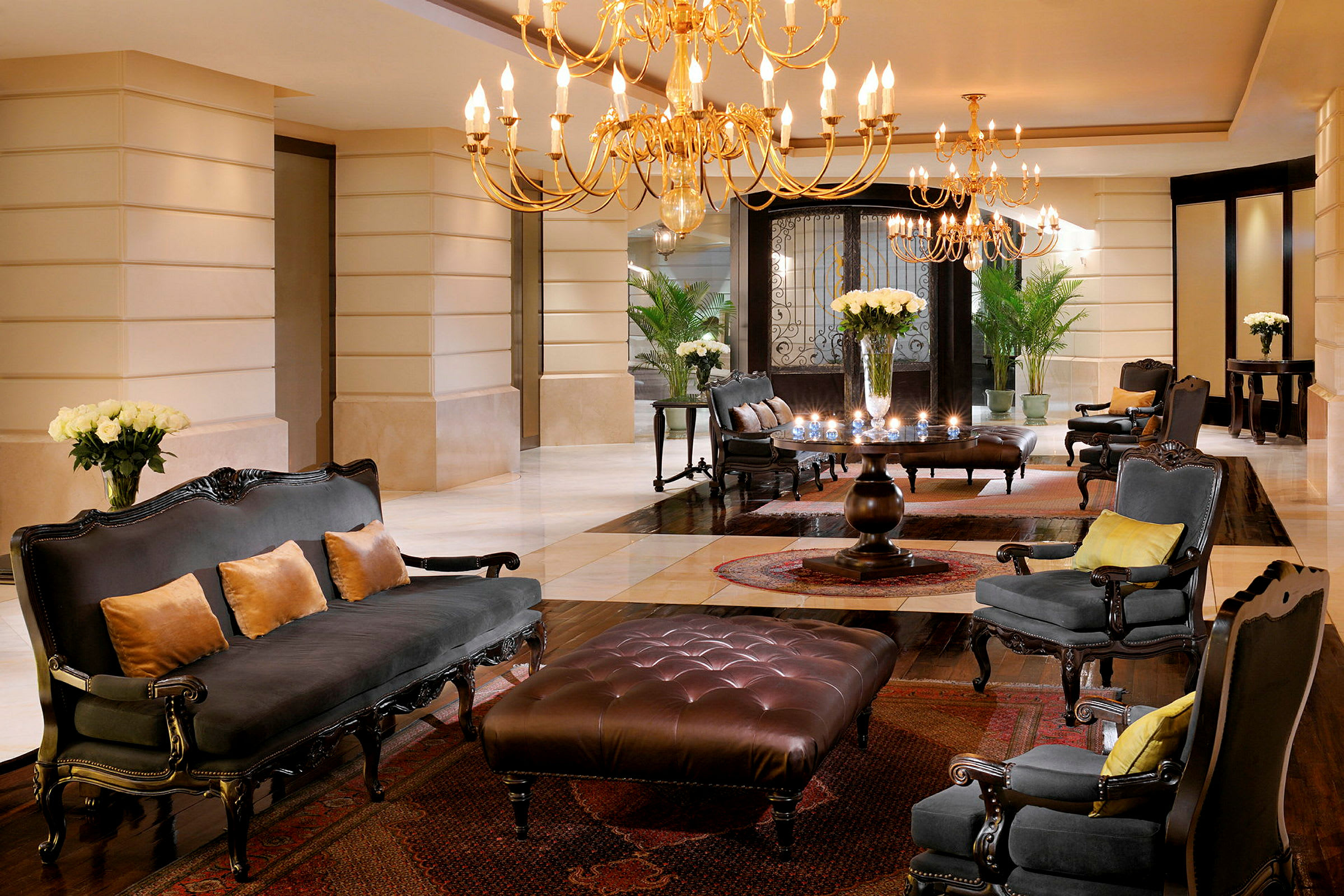 En elegant hotellobby med lysekroner, komfortable siddepladser og blomster på bordene. (AI-genereret tekst)