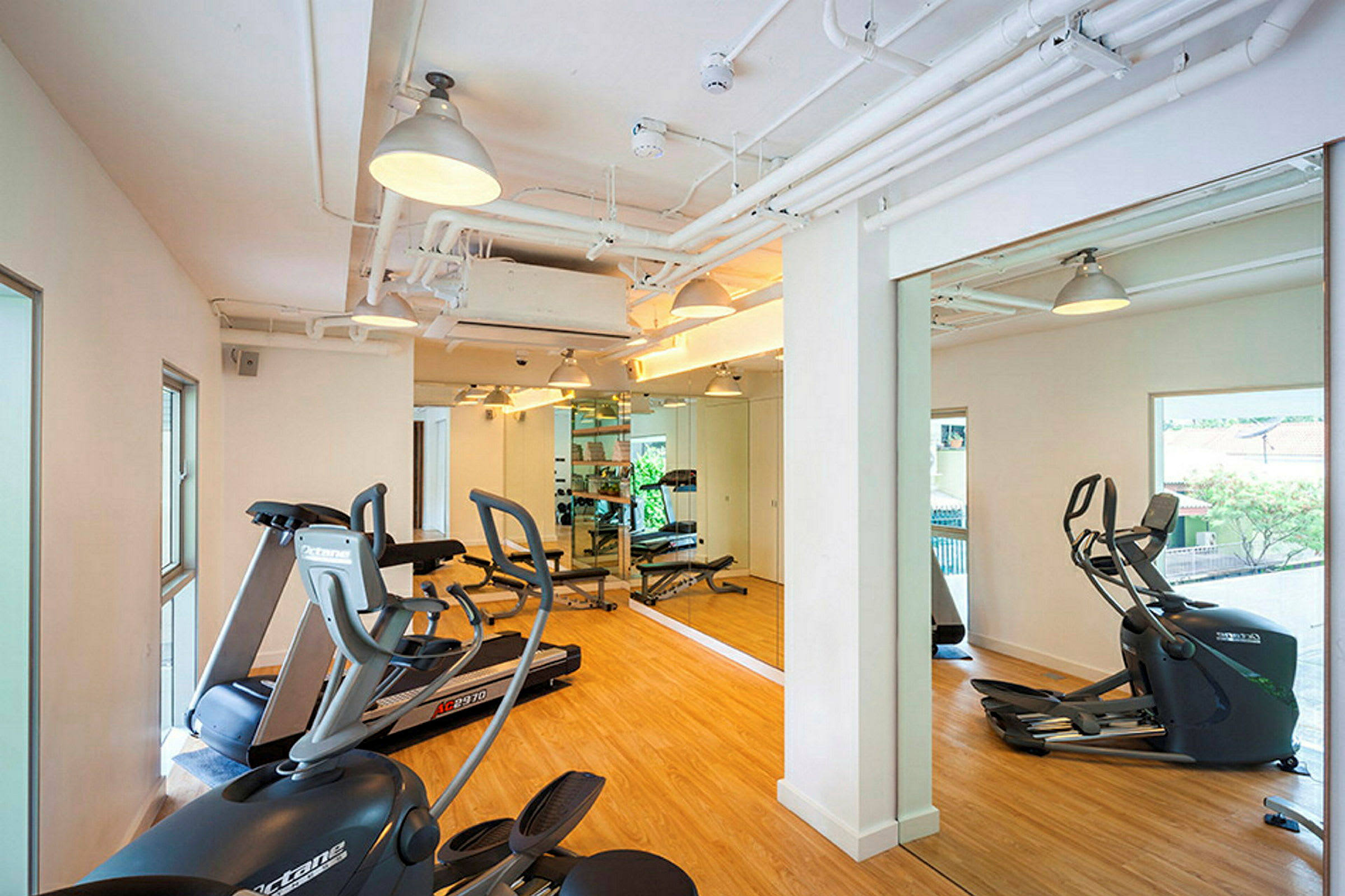Et lyst fitnessrum med spejlvæg og træningsudstyr såsom motionscykler og løbebånd. (AI-genereret tekst)