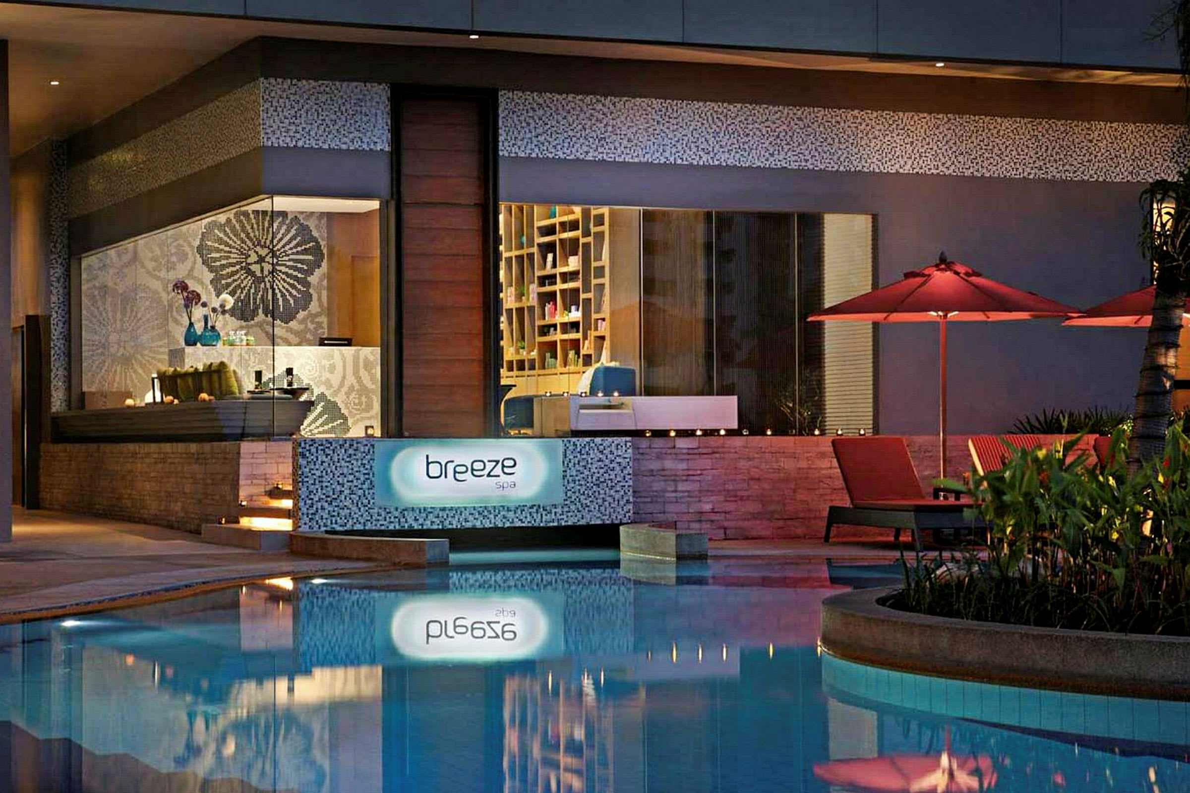 Spaområde med skiltet "Breeze Spa" samt røde parasoller og liggestole ved en pool. (AI-genereret tekst)
