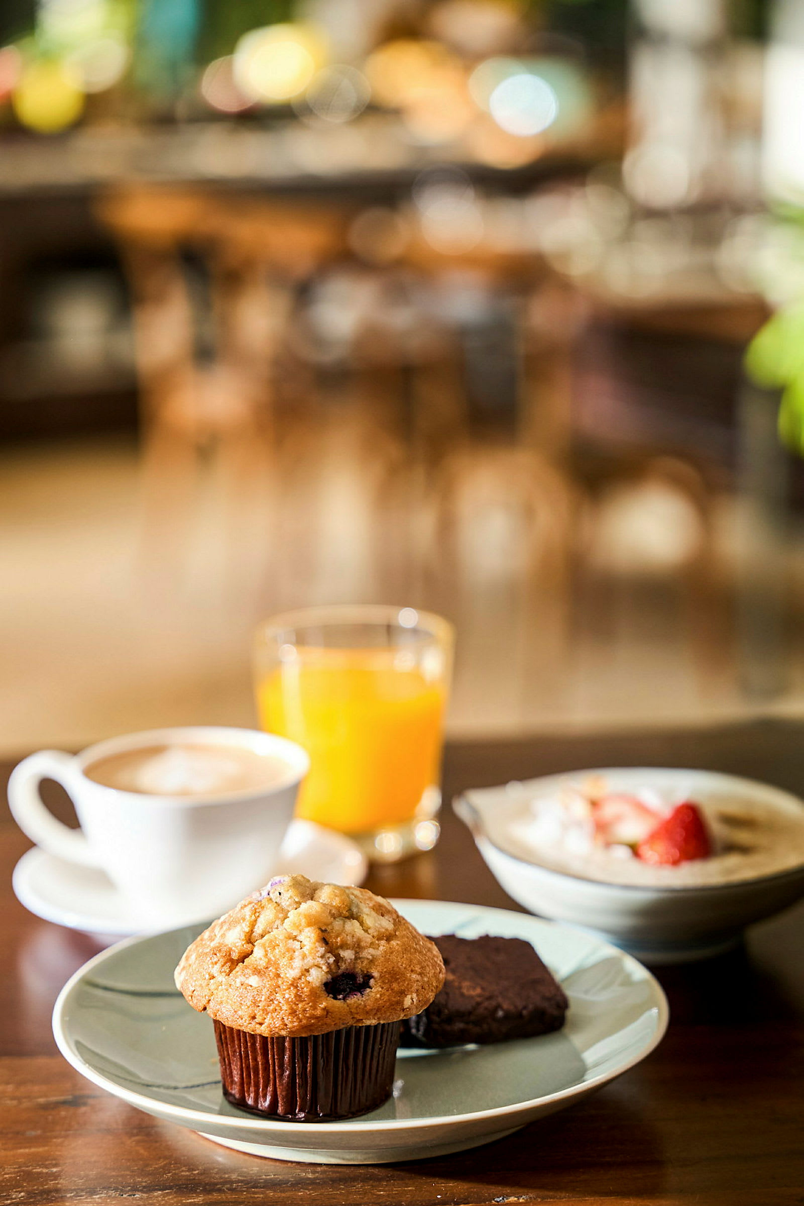 Morgenmad med muffin, brownie, kaffe, appelsinjuice og tallerken med jordbær. (AI-genereret tekst)