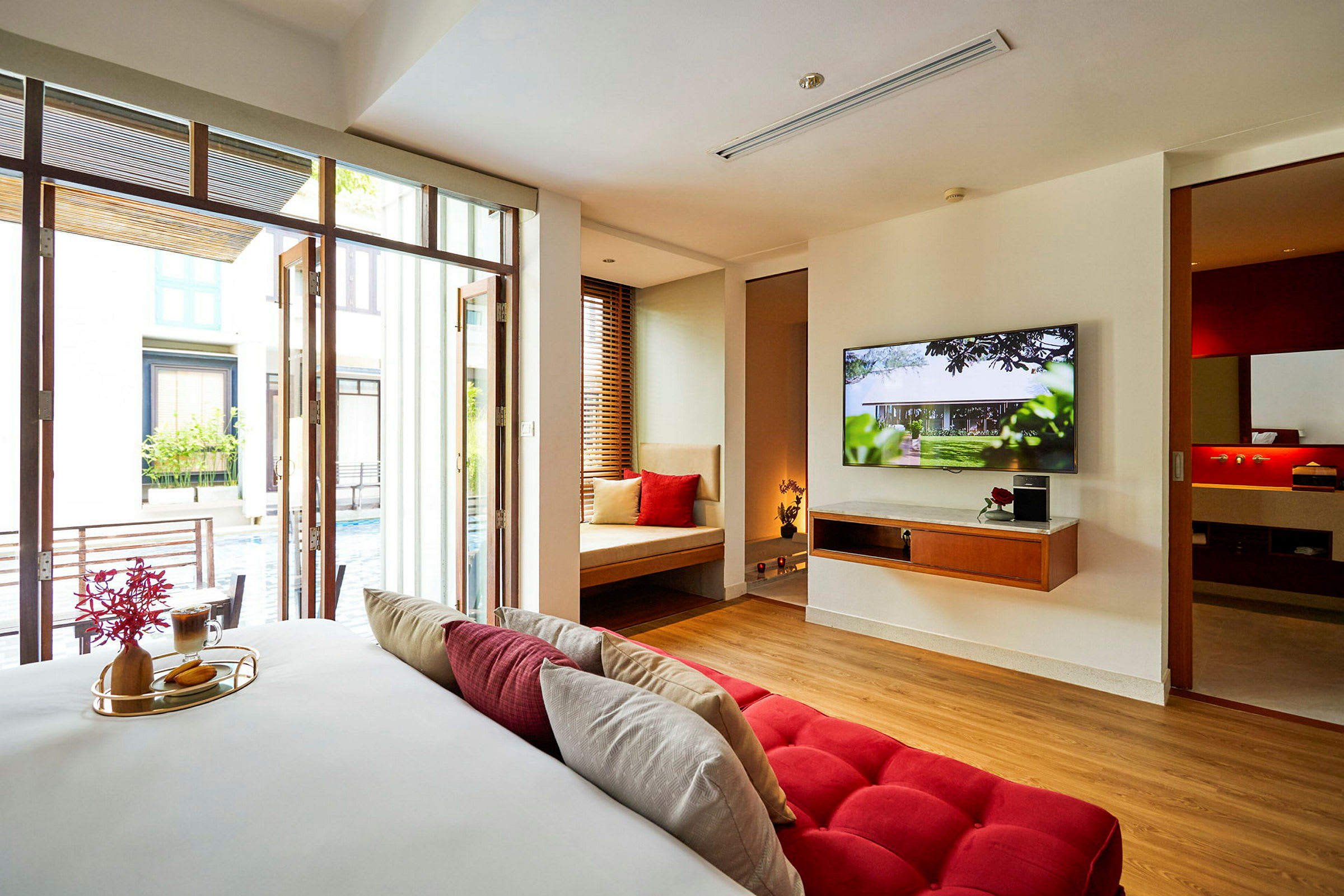 Et hotelværelse med moderne indretning, en stor TV og udsigt mod en pool. (AI-genereret tekst)