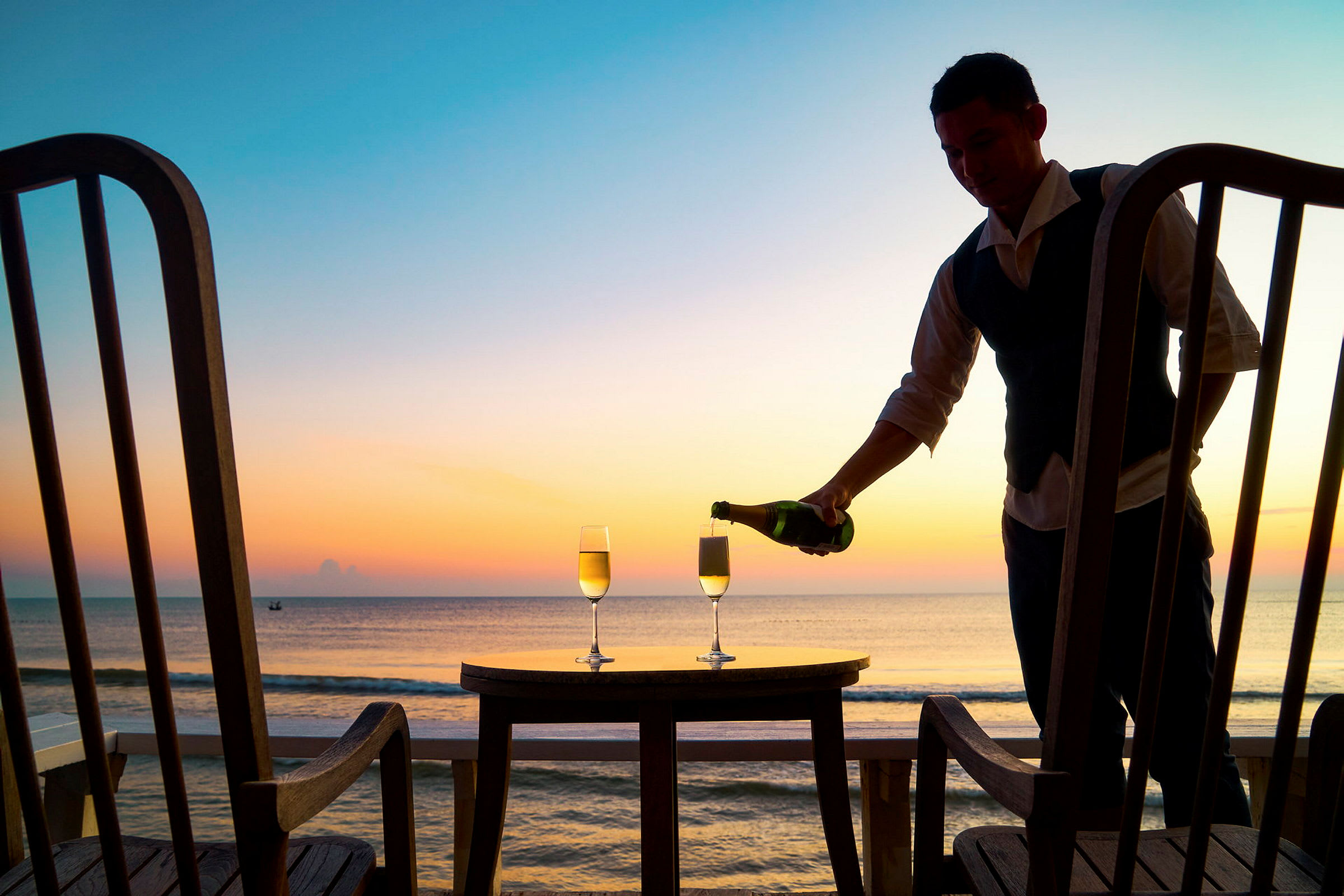 To glas champagne på et bord med havudsigt under solnedgang. (AI-genereret tekst)