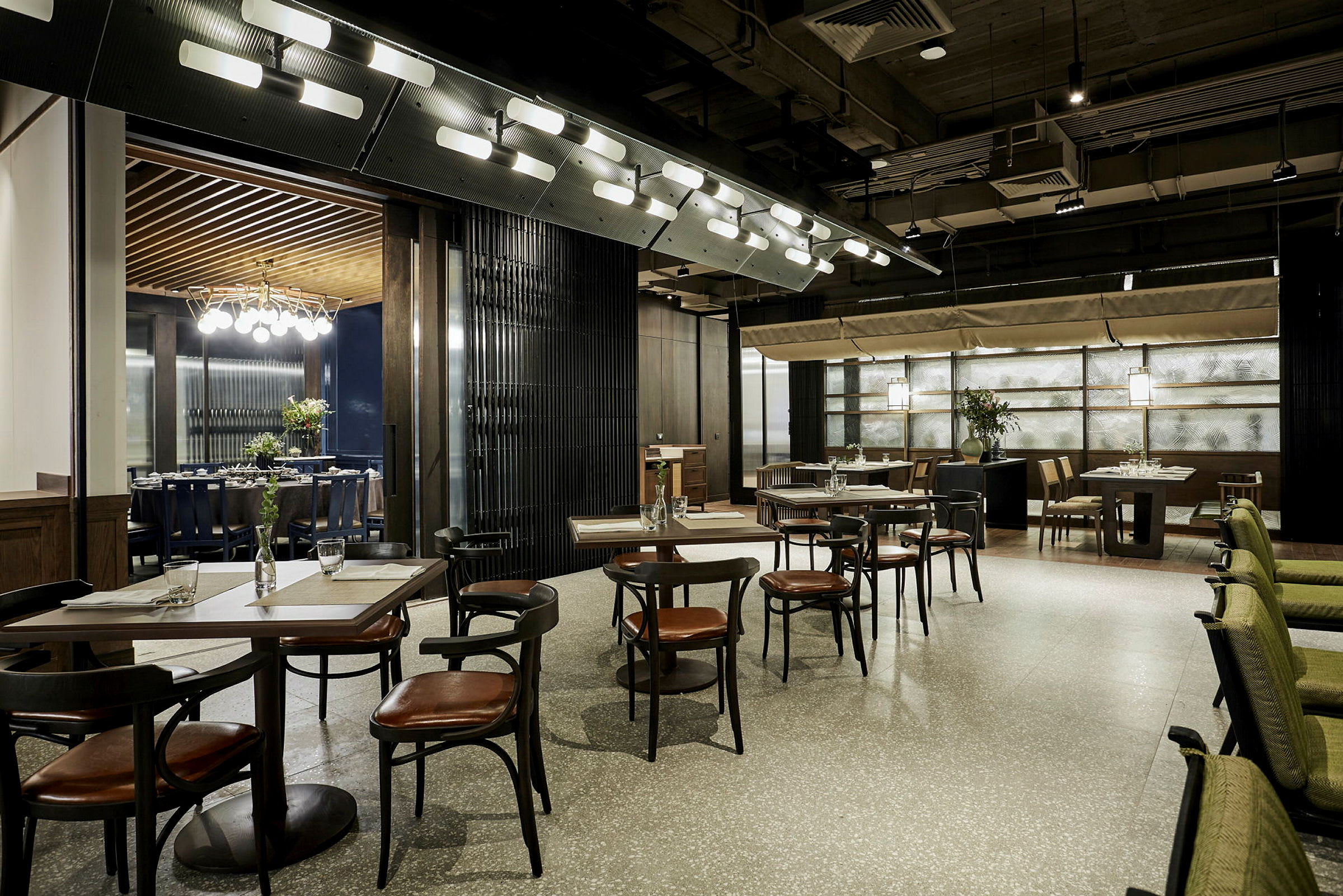 Et moderne og elegant restaurantmiljø med borde og stole arrangeret i en åben opsætning. Designet inkluderer stilrene detaljer og blød belysning. (AI-genereret tekst)