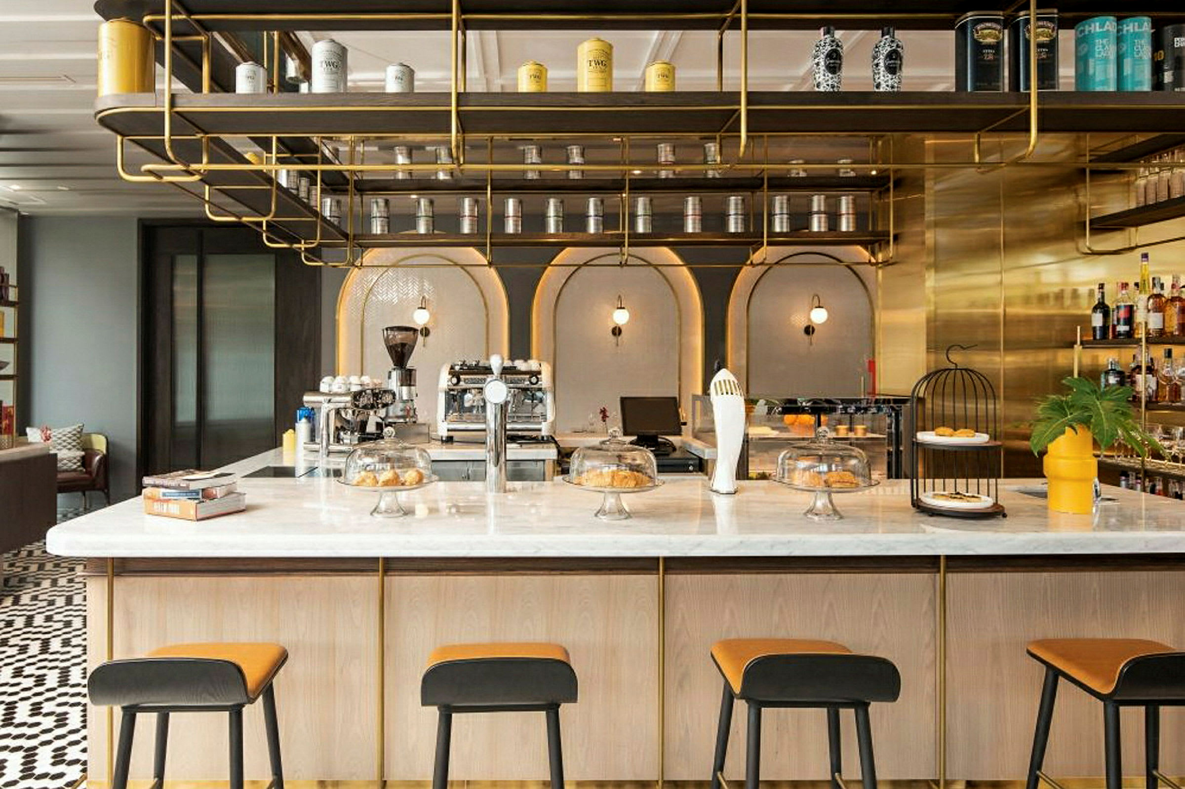En elegant café med moderne interiør, en marmordisk, høje stole og hylder dekoreret med dåser og flasker. (AI-genereret tekst)