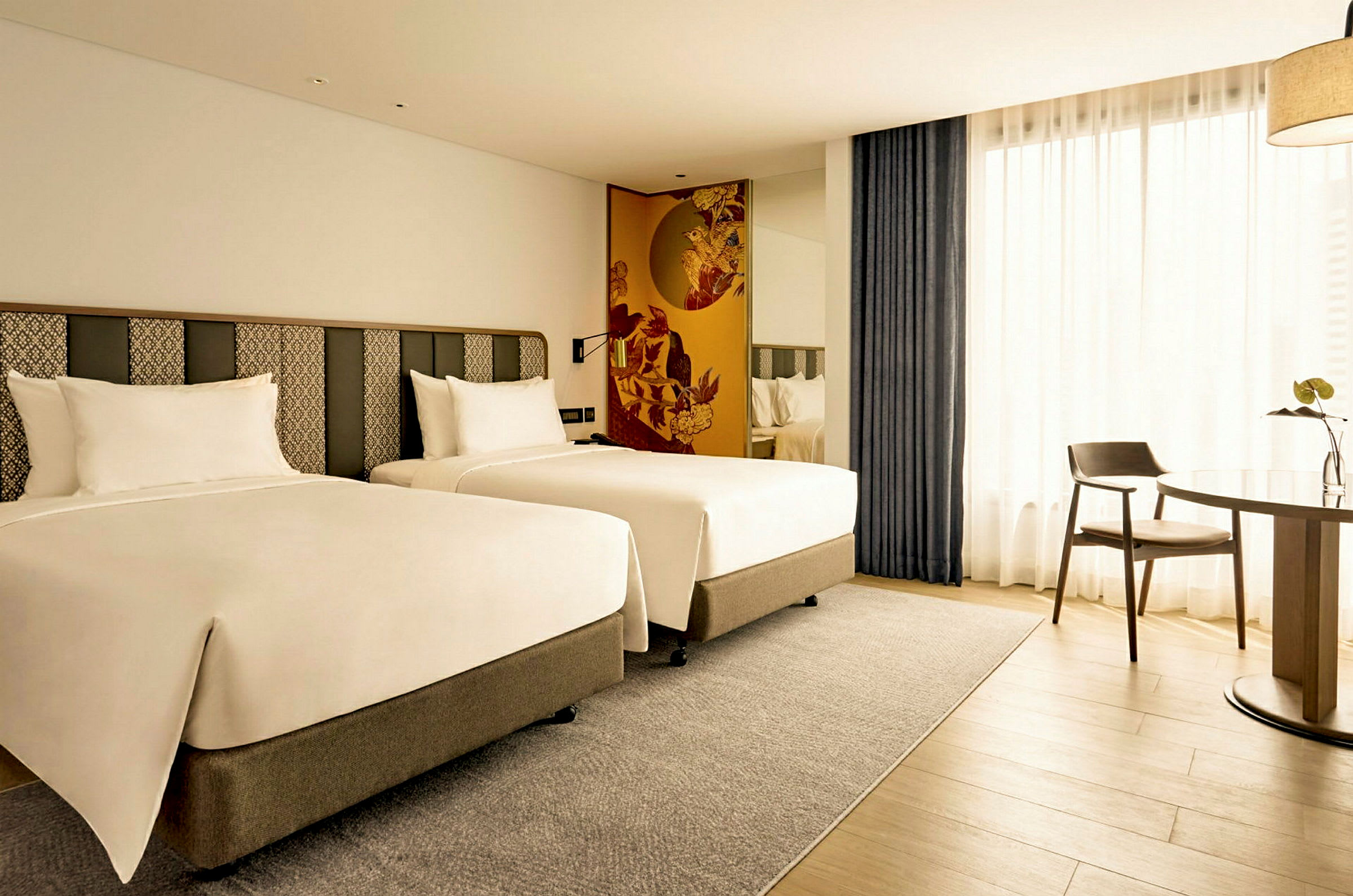 Hotelværelse med to enkeltsenge og et bord med en stol. (AI-genereret tekst)