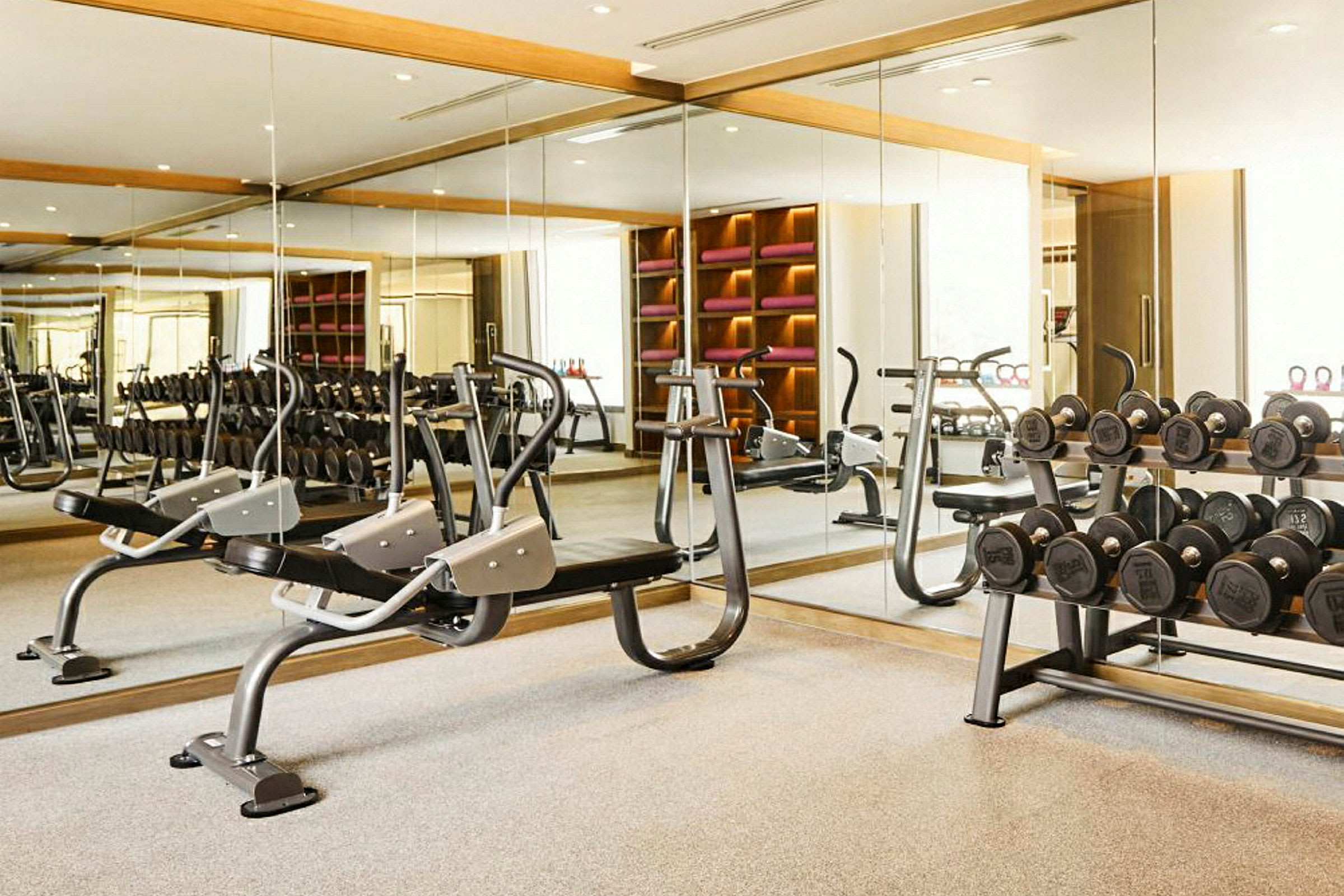 Et moderne fitnessrum med spejlvæg, træningsudstyr og håndvægte. (AI-genereret tekst)