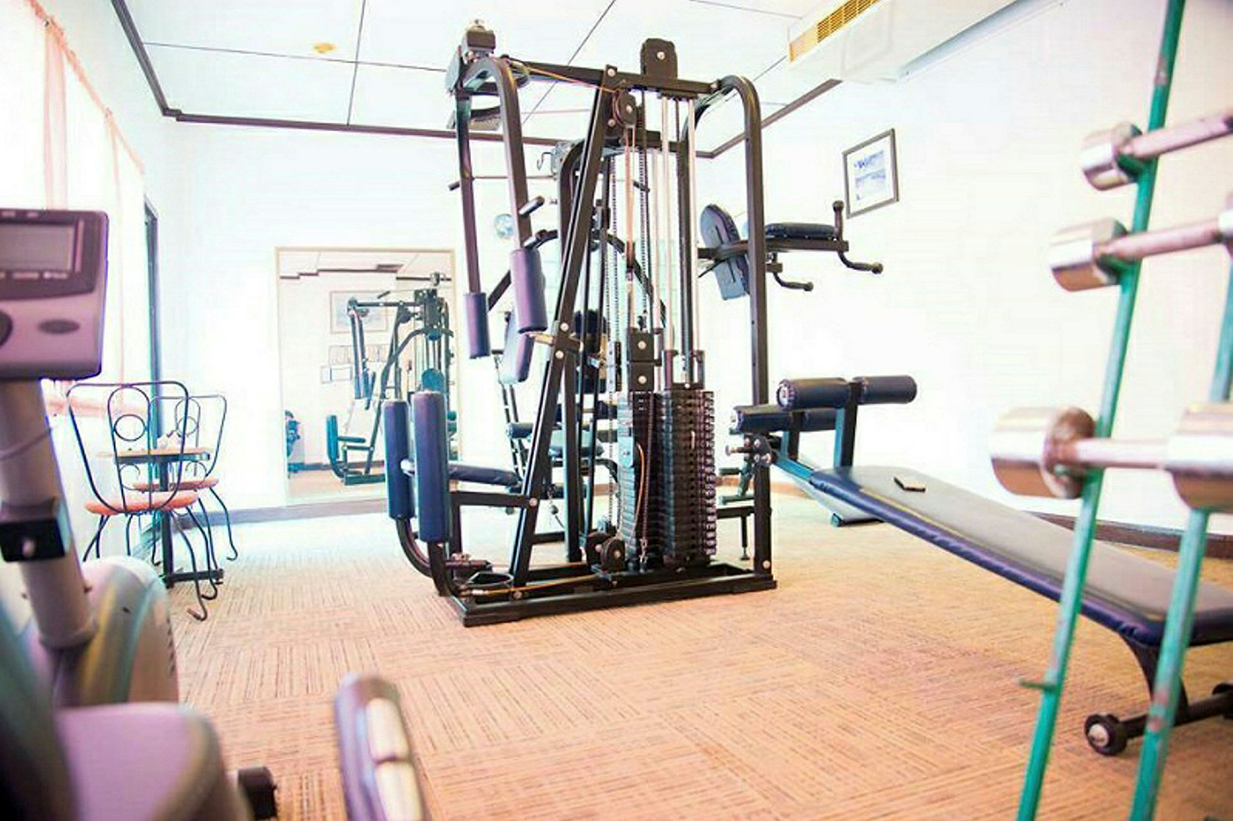 Et fitnesscenter med træningsudstyr såsom multistation, håndvægte og en træningsbænk. (AI-genereret tekst)