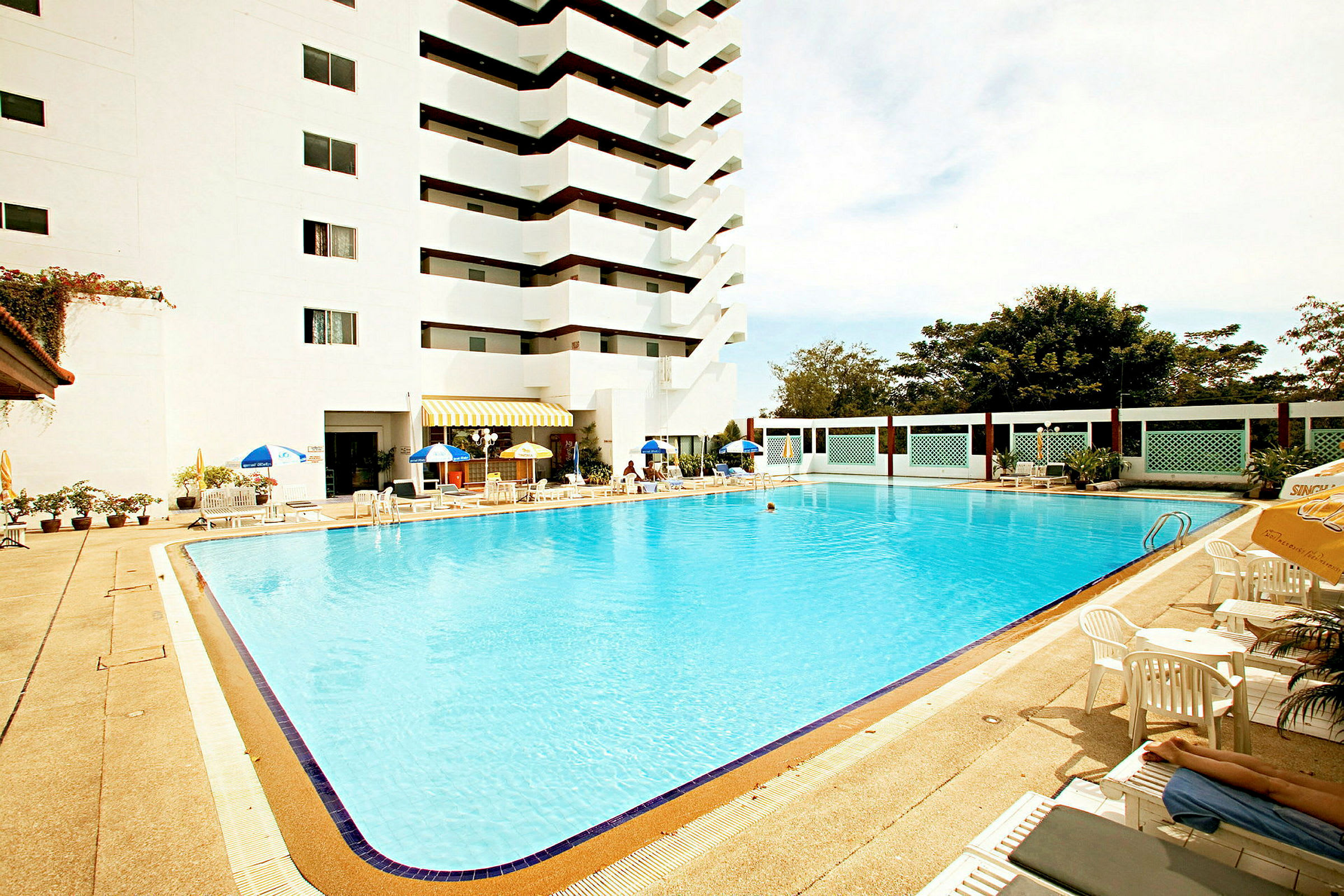 Udendørs pool ved et hotel med liggestole og parasoller. (AI-genereret tekst)