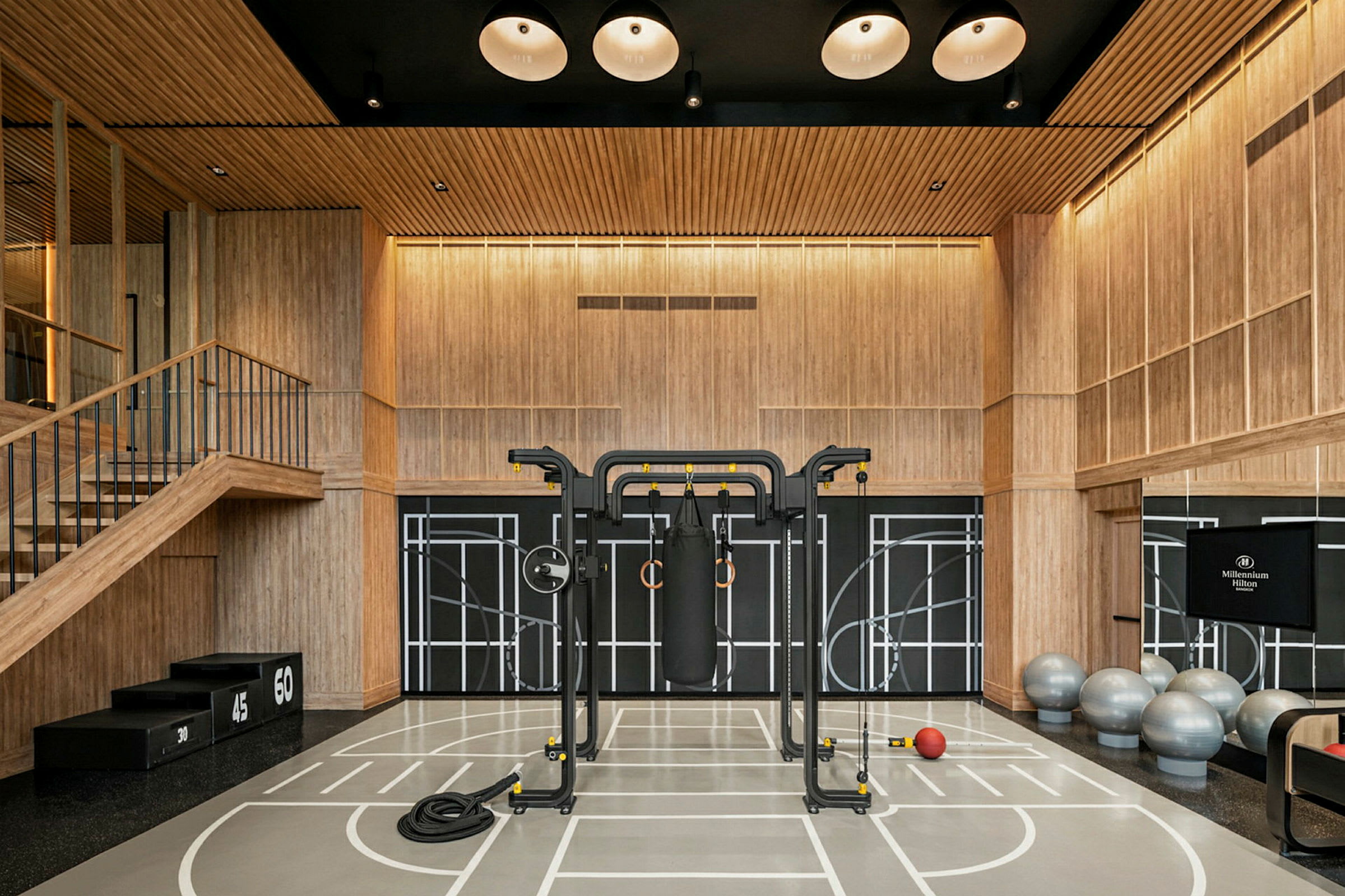 Et fitnesscenter med træpaneler og træningsudstyr, herunder fitnessbolde, en boksebold og et stativ. (AI-genereret tekst)