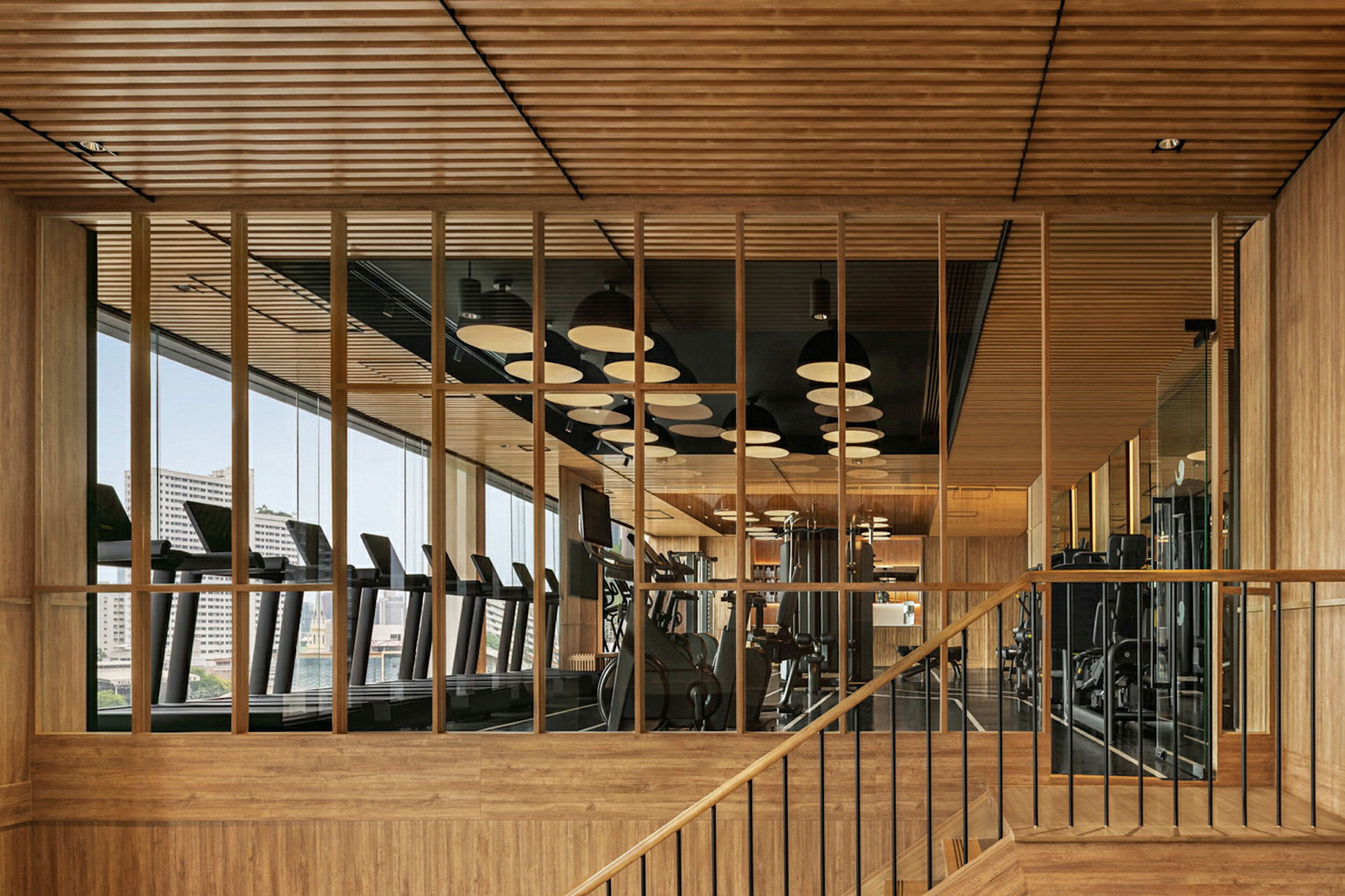 Et moderne fitnesscenter med trædetaljer og store vinduer. (AI-genereret tekst)