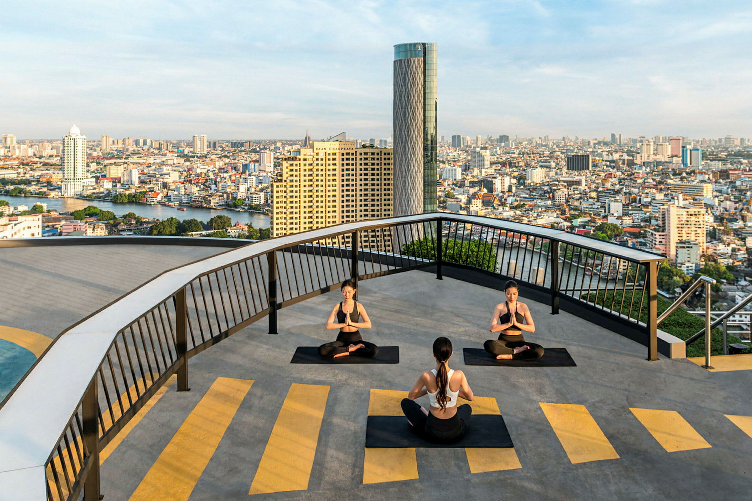 Personer, der udfører yoga på en tagterrasse med udsigt over en by. (AI-genereret tekst)
