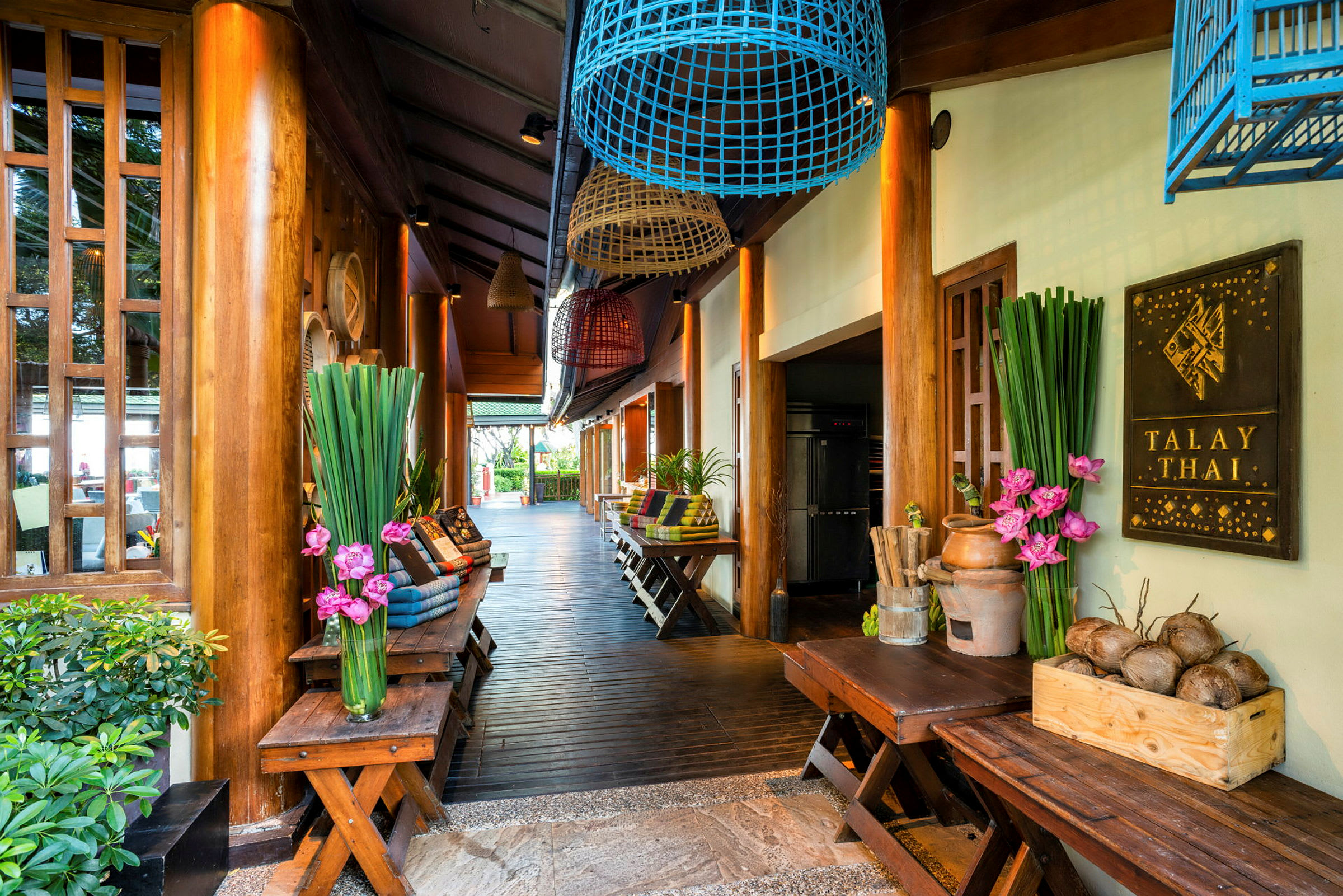 Indgang til en thailandsk restaurant med trædetaljer, planter og dekorationer. (AI-genereret tekst)