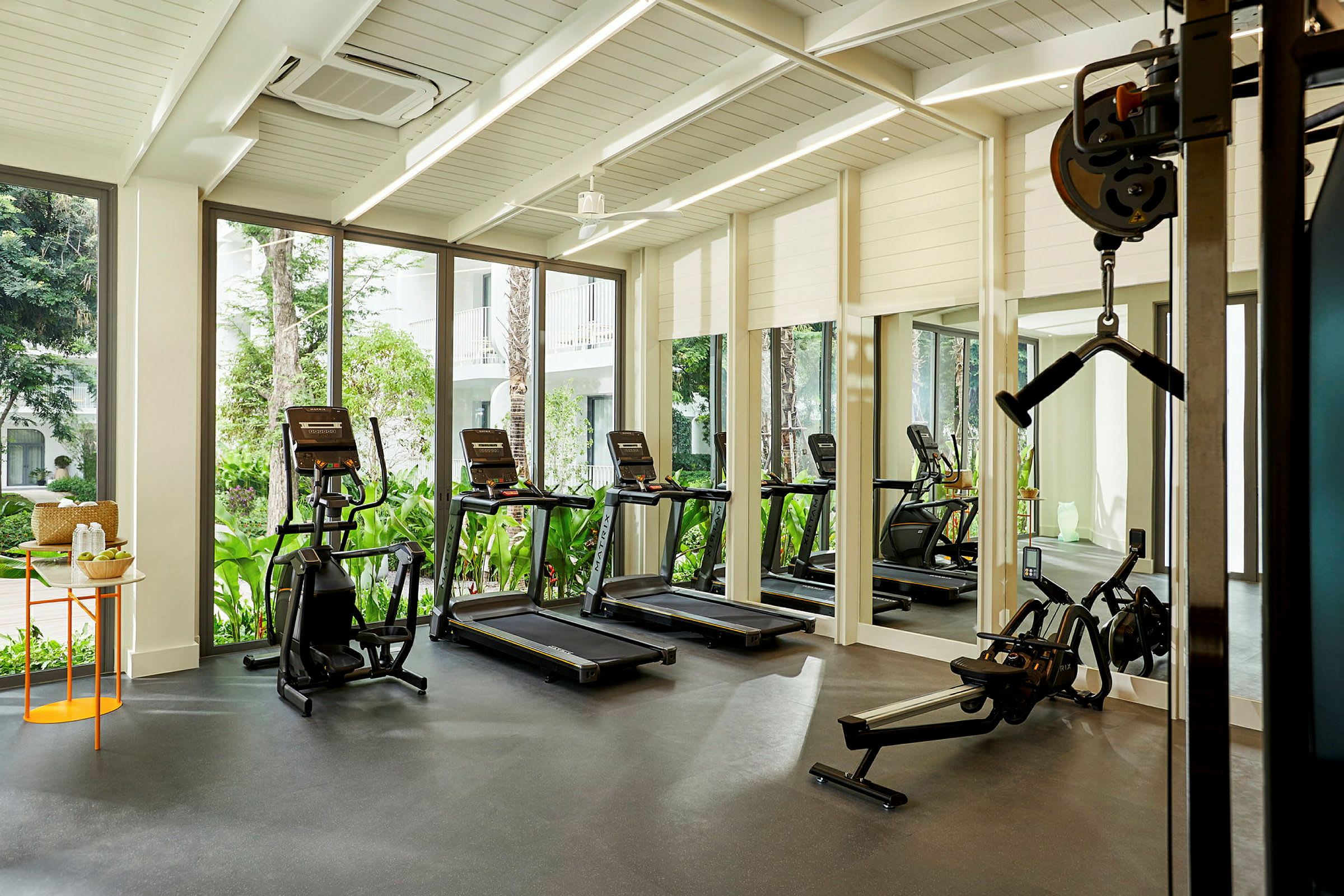 Moderne fitnesscenter med træningsmaskiner, store vinduer og naturligt lysindfald. (AI-genereret tekst)