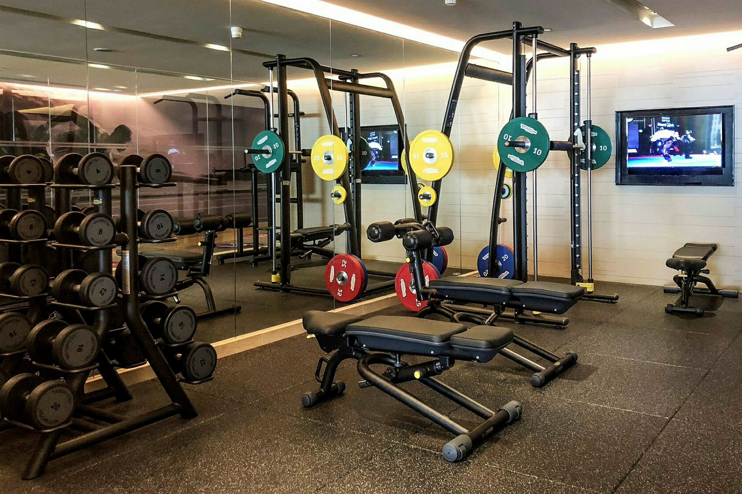 Billede af et fitnesscenter med træningsudstyr som vægte, bænke og maskiner. (AI-genereret tekst)