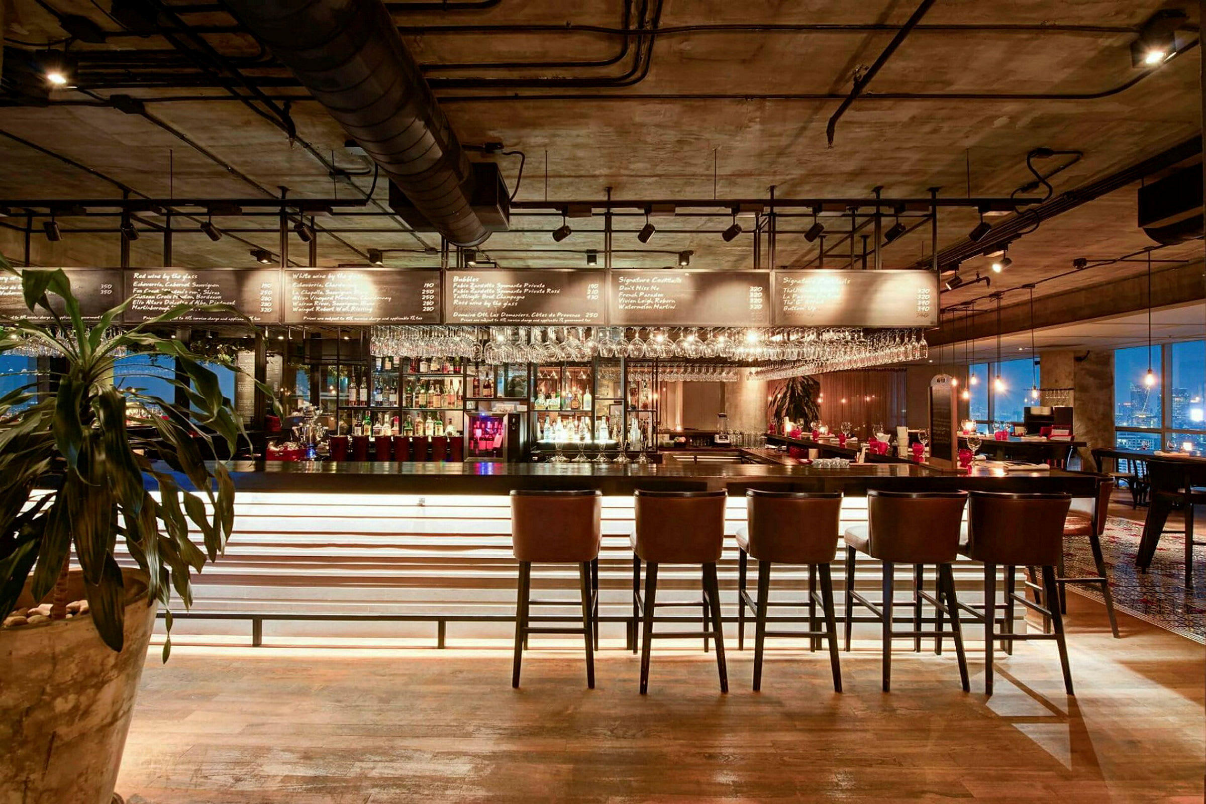Interiør af en moderne bar med stole ved en bardisk og hylder med flasker og glas. (AI-genereret tekst)