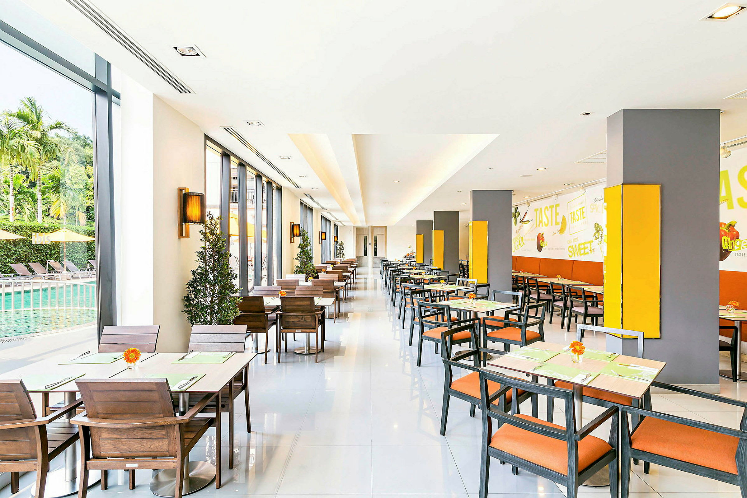 En lys restaurant med siddepladser, vinduer ud mod en pool og vægdekorationer. (AI-genereret tekst)