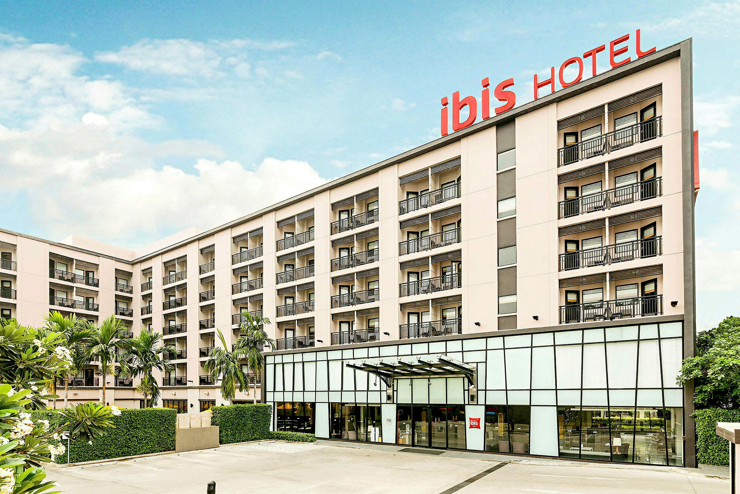 Hotelbygning med flere etager og altaner, skilt med teksten 'ibis HOTEL'. (AI-genereret tekst)