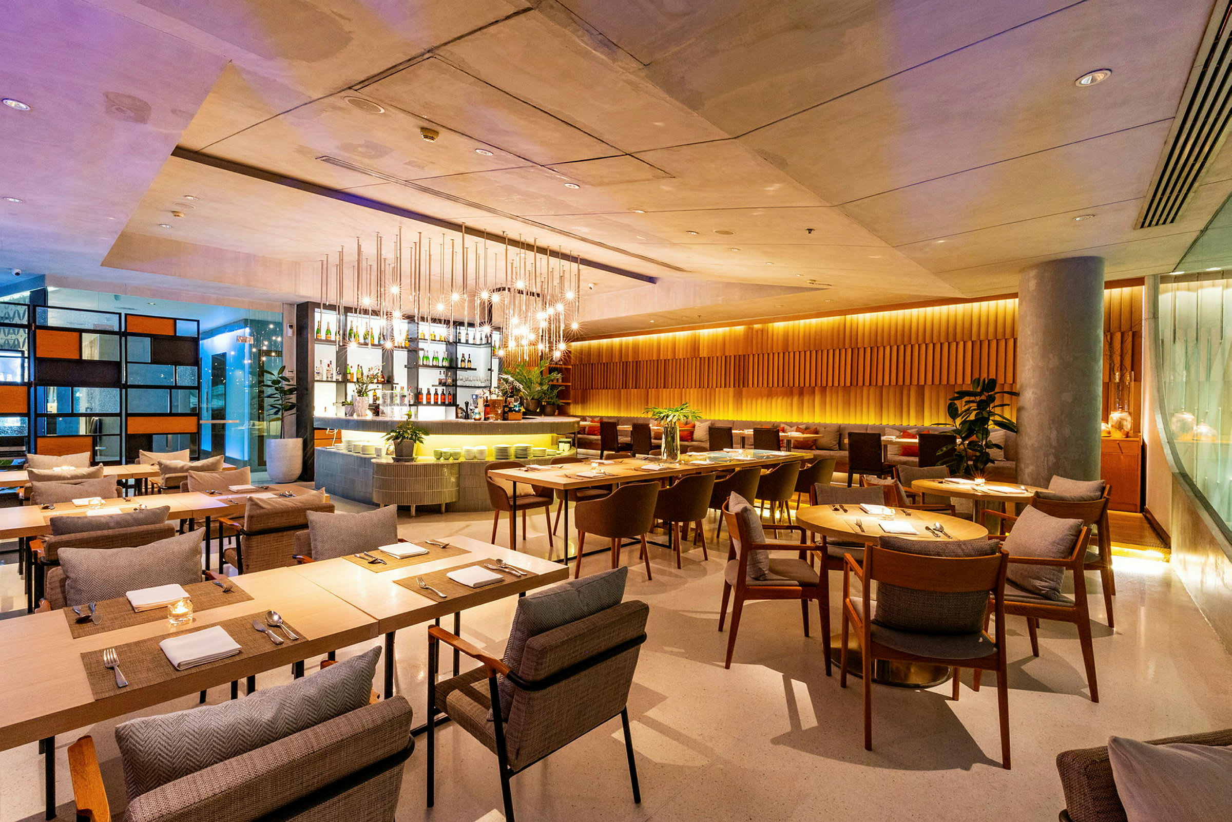 En moderne restaurant med træborde, komfortable stole og en stilfuld bar i baggrunden. (AI-genereret tekst)