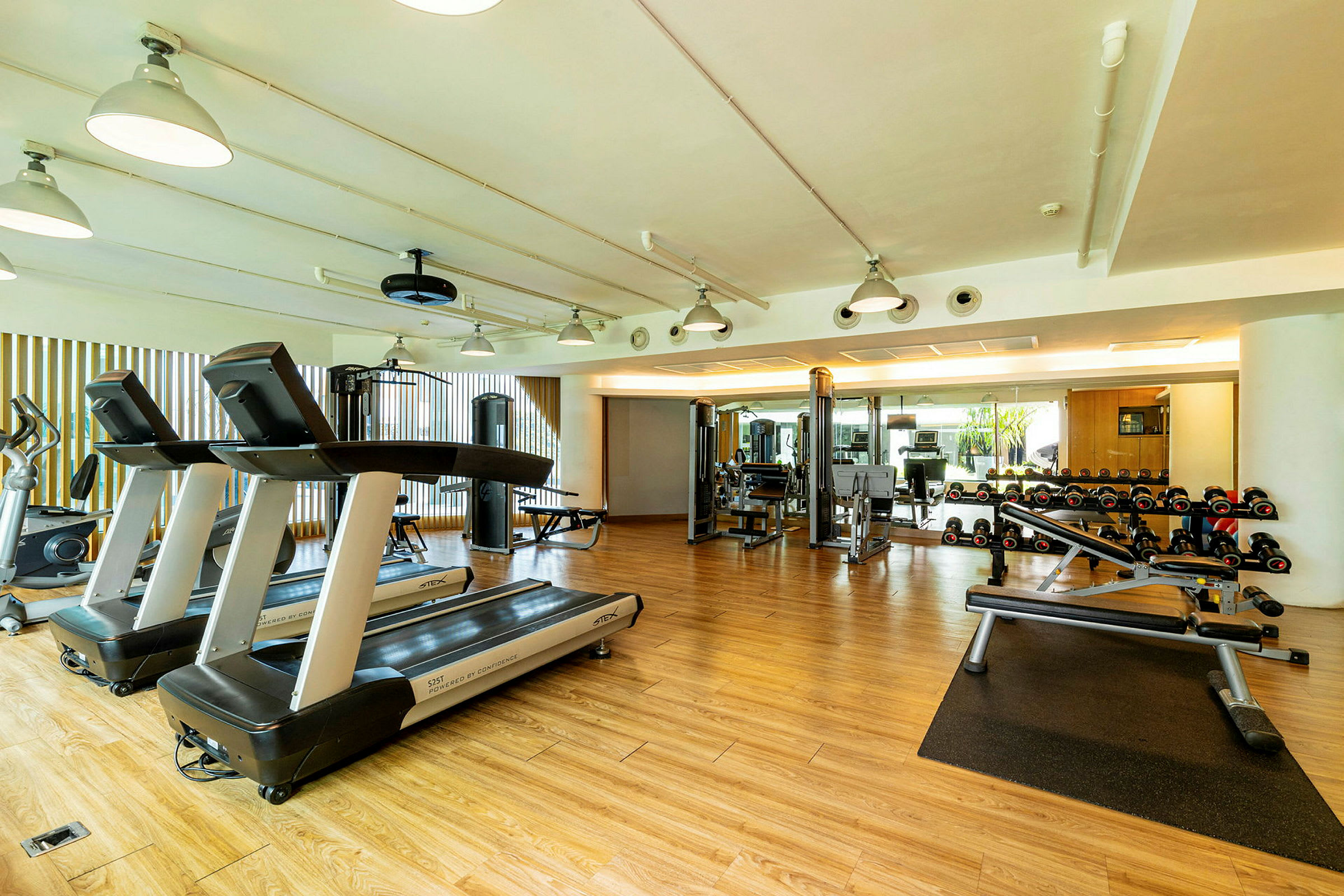 Et fitnesscenter med træningsmaskiner, løbebånd og håndvægte. (AI-genereret tekst)