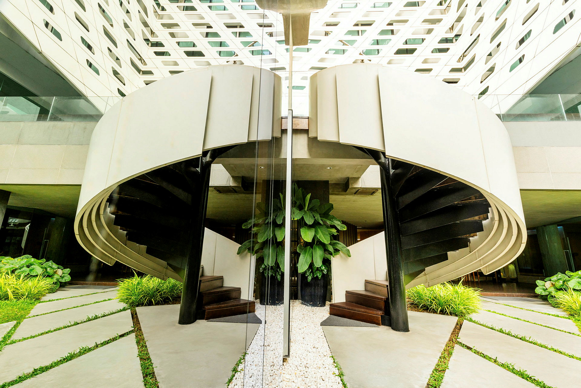 Billede af en moderne spiraltrappe med planter og hvid arkitektur. (AI-genereret tekst)