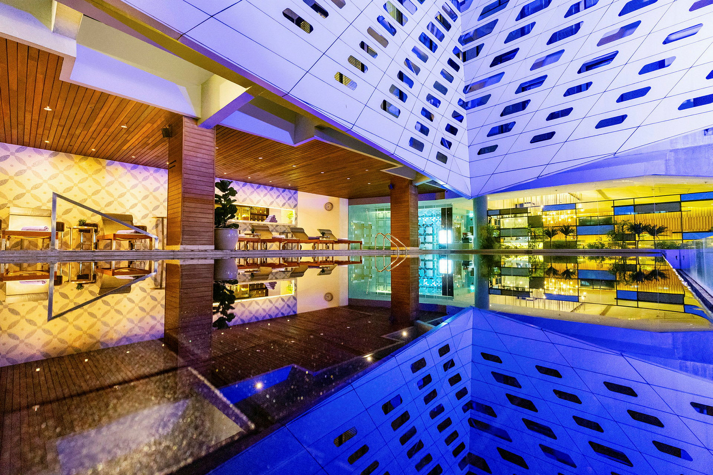 Et moderne hotel med en oplyst indretning og et spejlbassin, der reflekterer bygningen. (AI-genereret tekst)
