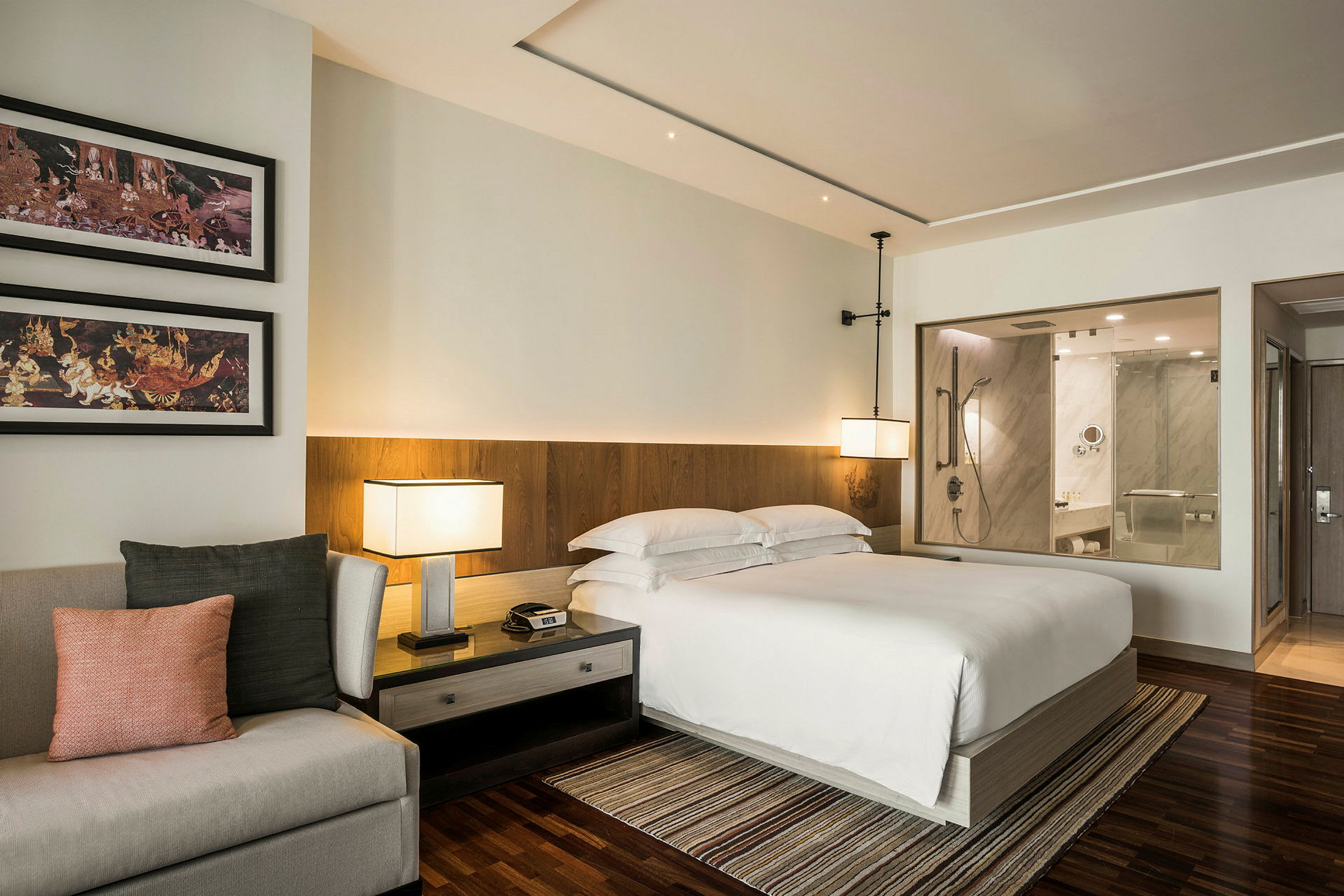 Et moderne hotelværelse med en dobbeltseng, en sofa, natbord og et åbent design, der viser et badeværelse. (AI-genereret tekst)