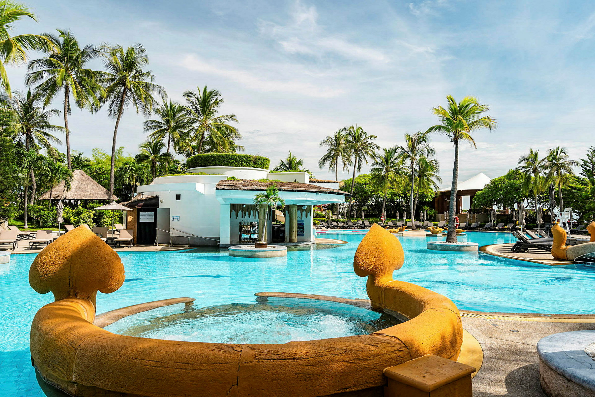 Udendørs pool med springvand på en resort omgivet af palmer. (AI-genereret tekst)