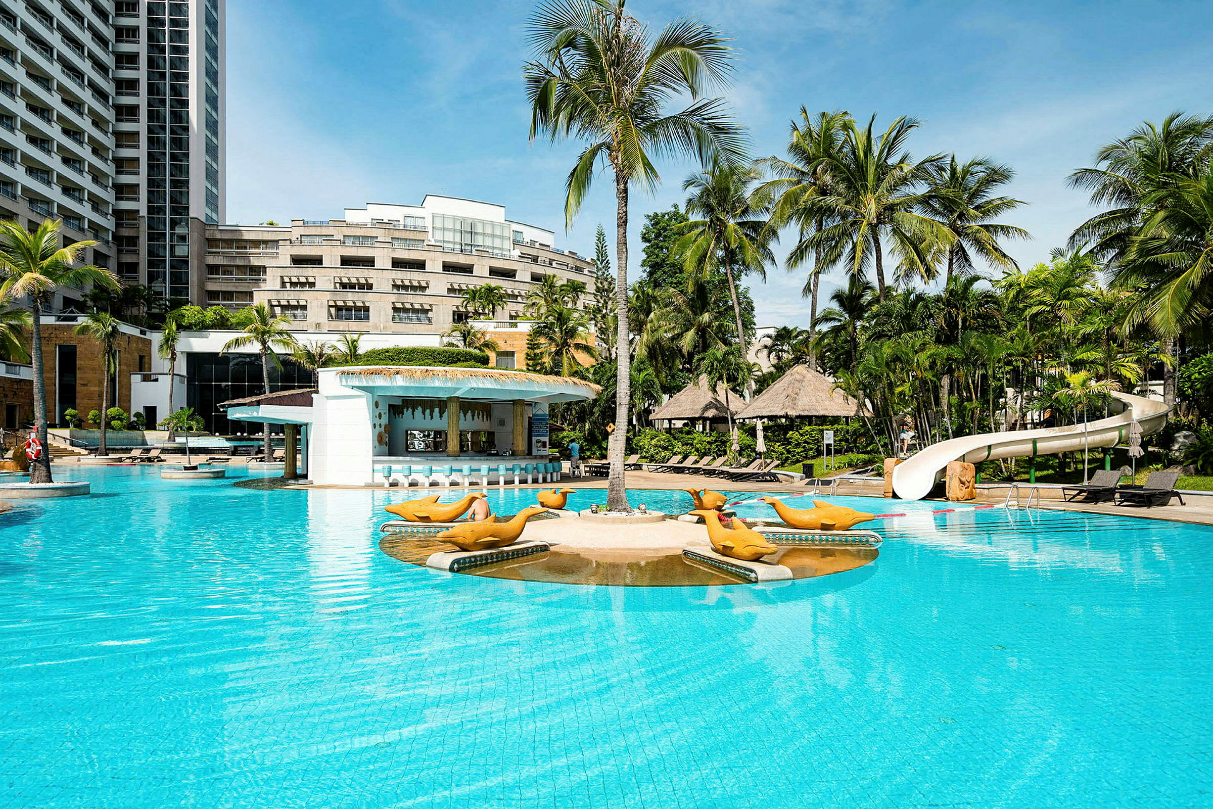 Billede af en hotelpool med palmer og liggestole i baggrunden. En legeplads og vandrutsjebane kan ses ved kanten af poolen. (AI-genereret tekst)