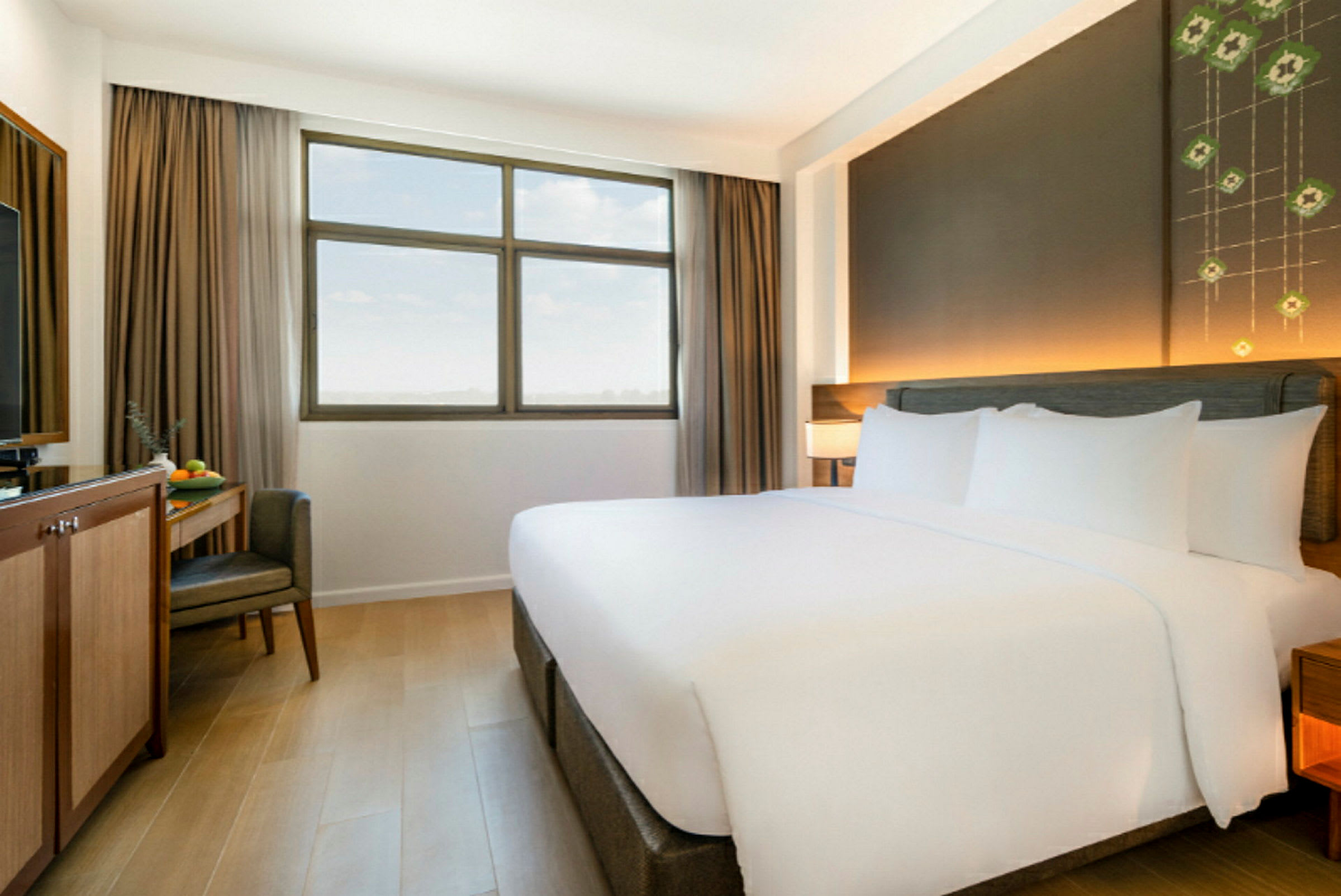 Et hotelværelse med en stor dobbeltseng, et vindue med beige gardiner og et skrivebord med en stol og en tv. (AI-genereret tekst)