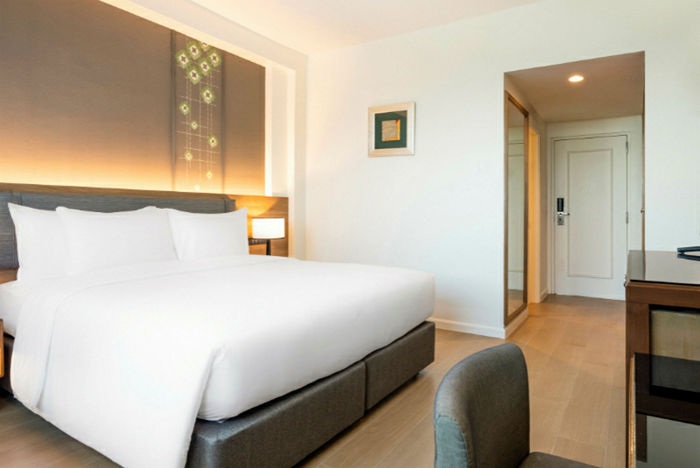 Et moderne hotelværelse med en stor seng med hvide lagner og en sengegavl med indbygget belysning. (AI-genereret tekst)