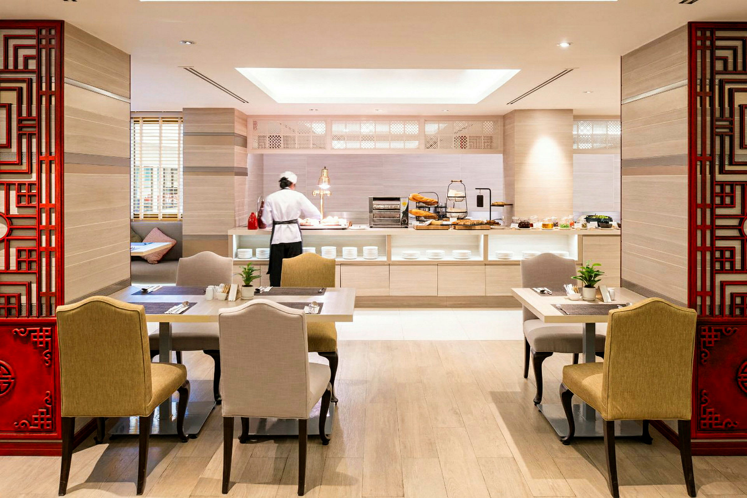 Interiør med spiseområde og buffet, hvor en kok står ved bordet. (AI-genereret tekst)