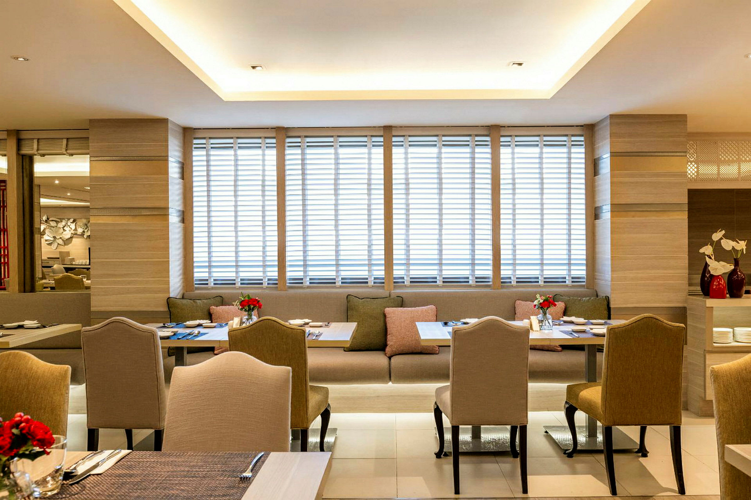 Billede af en moderne restaurant med elegante stole og borde samt sofaarrangementer, dekoreret med friske blomster. (AI-genereret tekst)