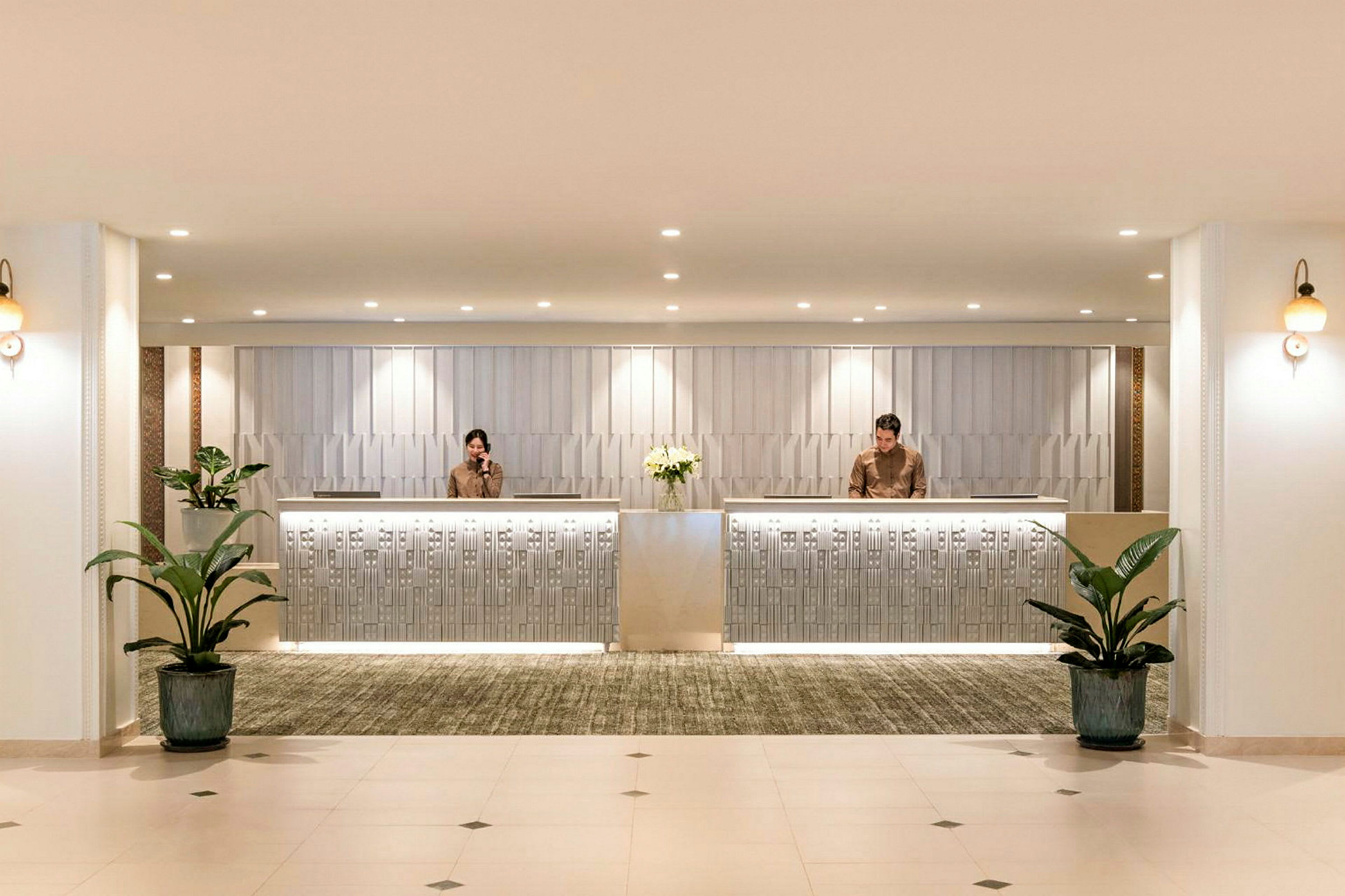 Reception med to receptionister, moderne indretning og planter. (AI-genereret tekst)