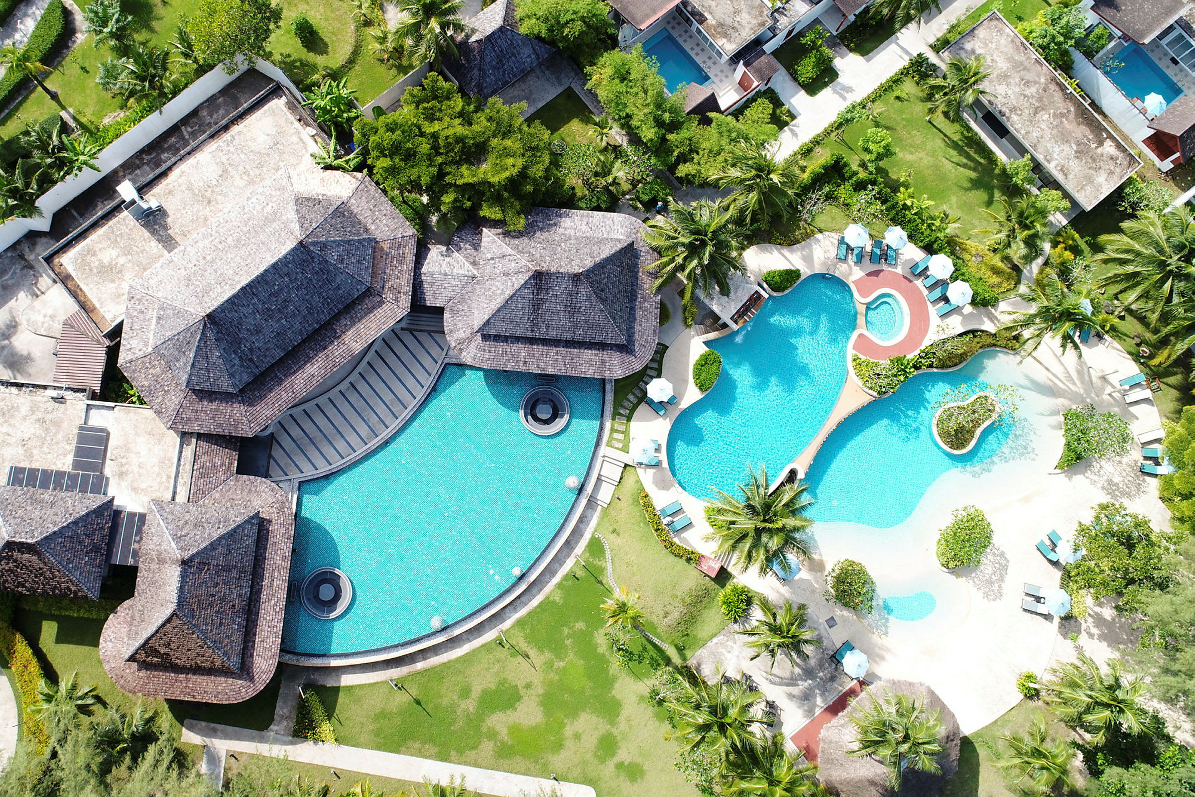 Fugleperspektiv af en resort med swimmingpools og grønne områder. (AI-genereret tekst)