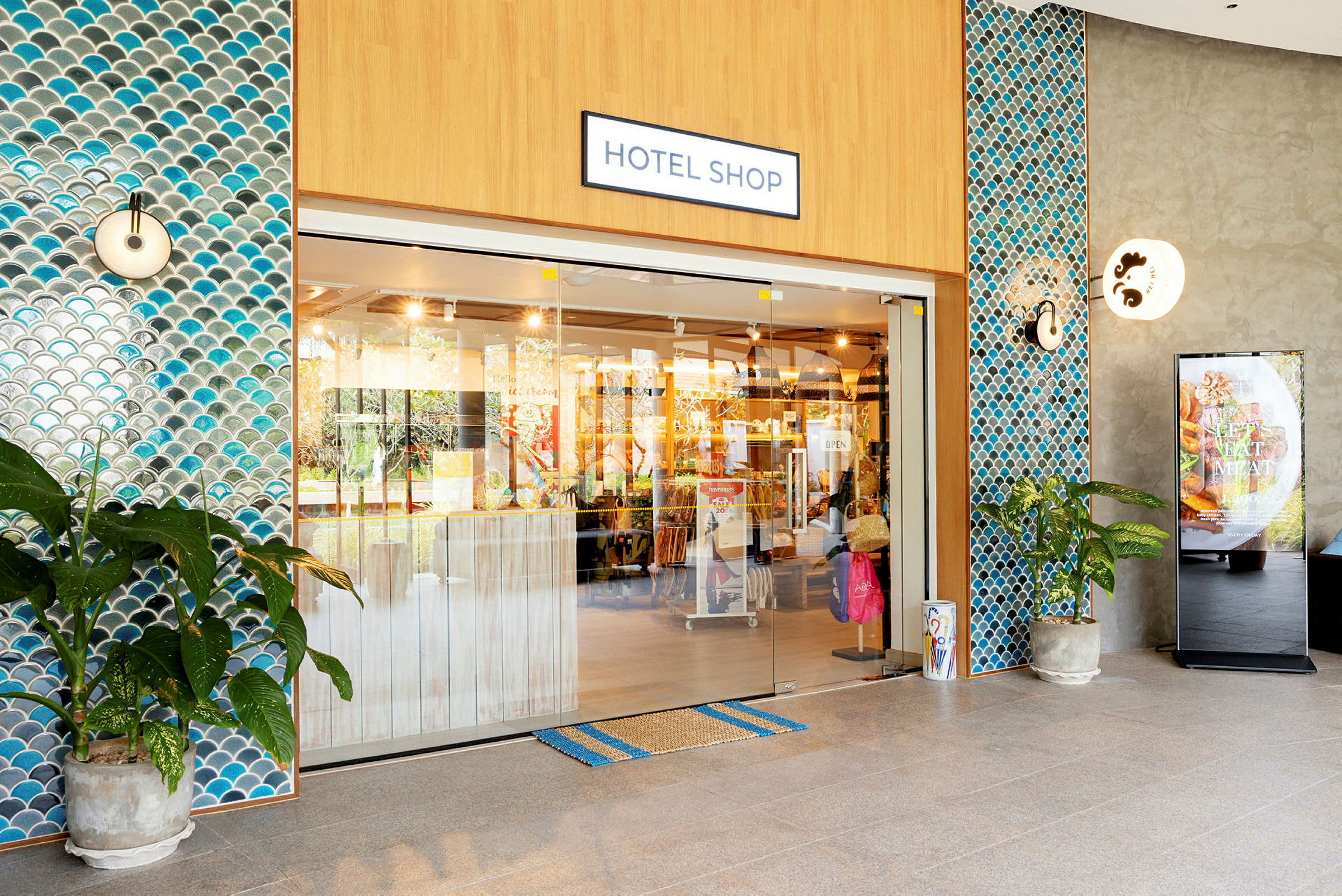 Indgangen til en hotelbutik med glasdøre og flisebelagte vægge. (AI-genereret tekst)