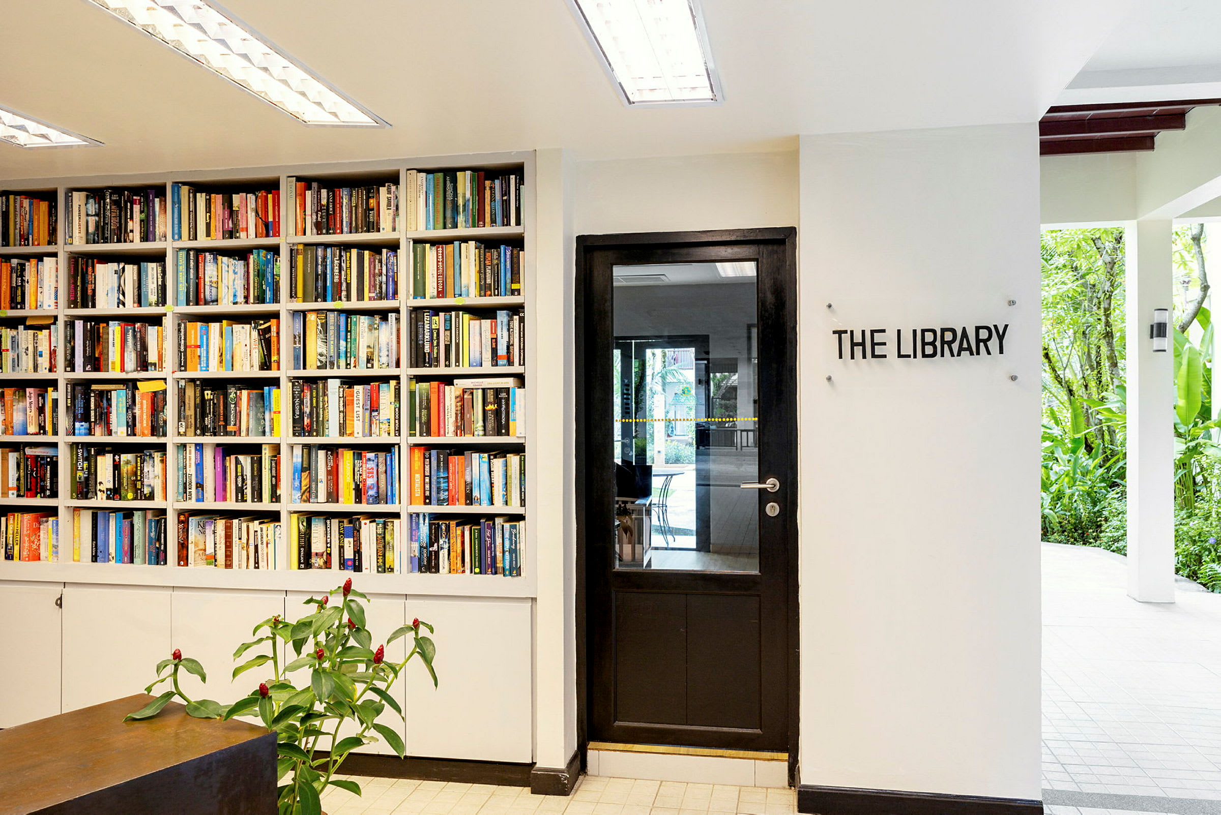 En bogreol fyldt med bøger ved siden af en dør med skiltet "The Library". (AI-genereret tekst)