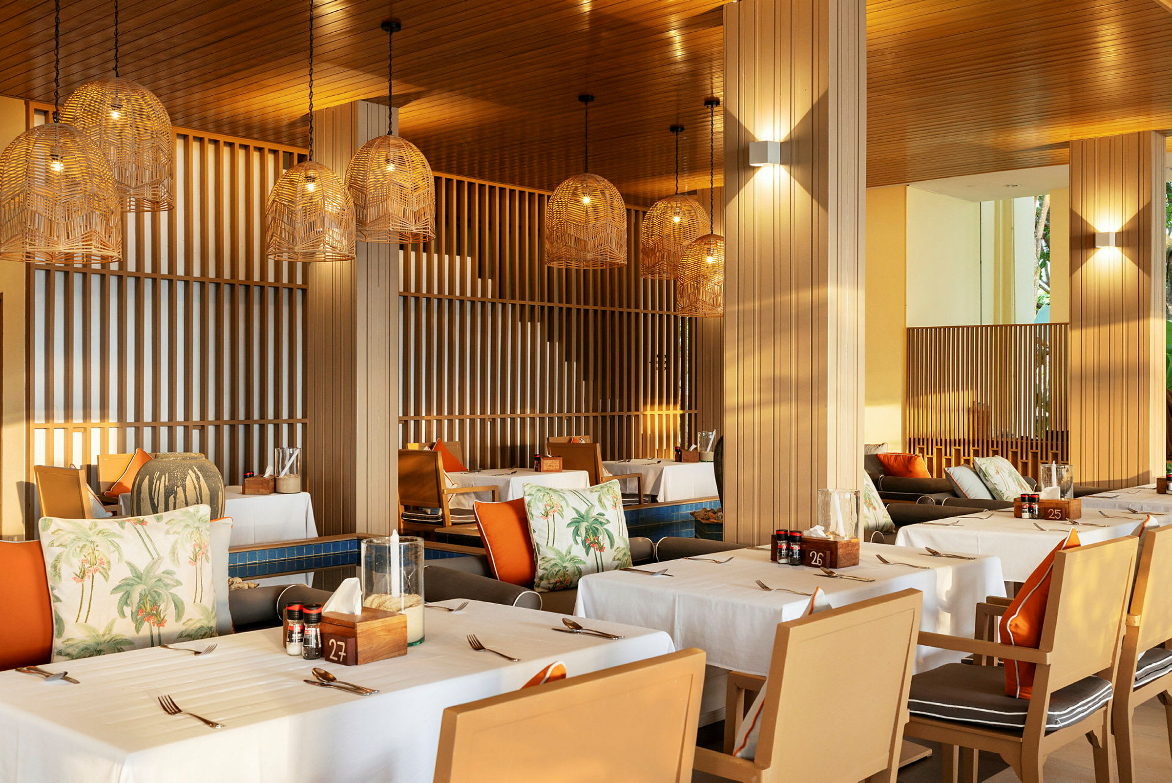 En restaurant med dækkede borde og hængende lampeskærme i flettet design. (AI-genereret tekst)