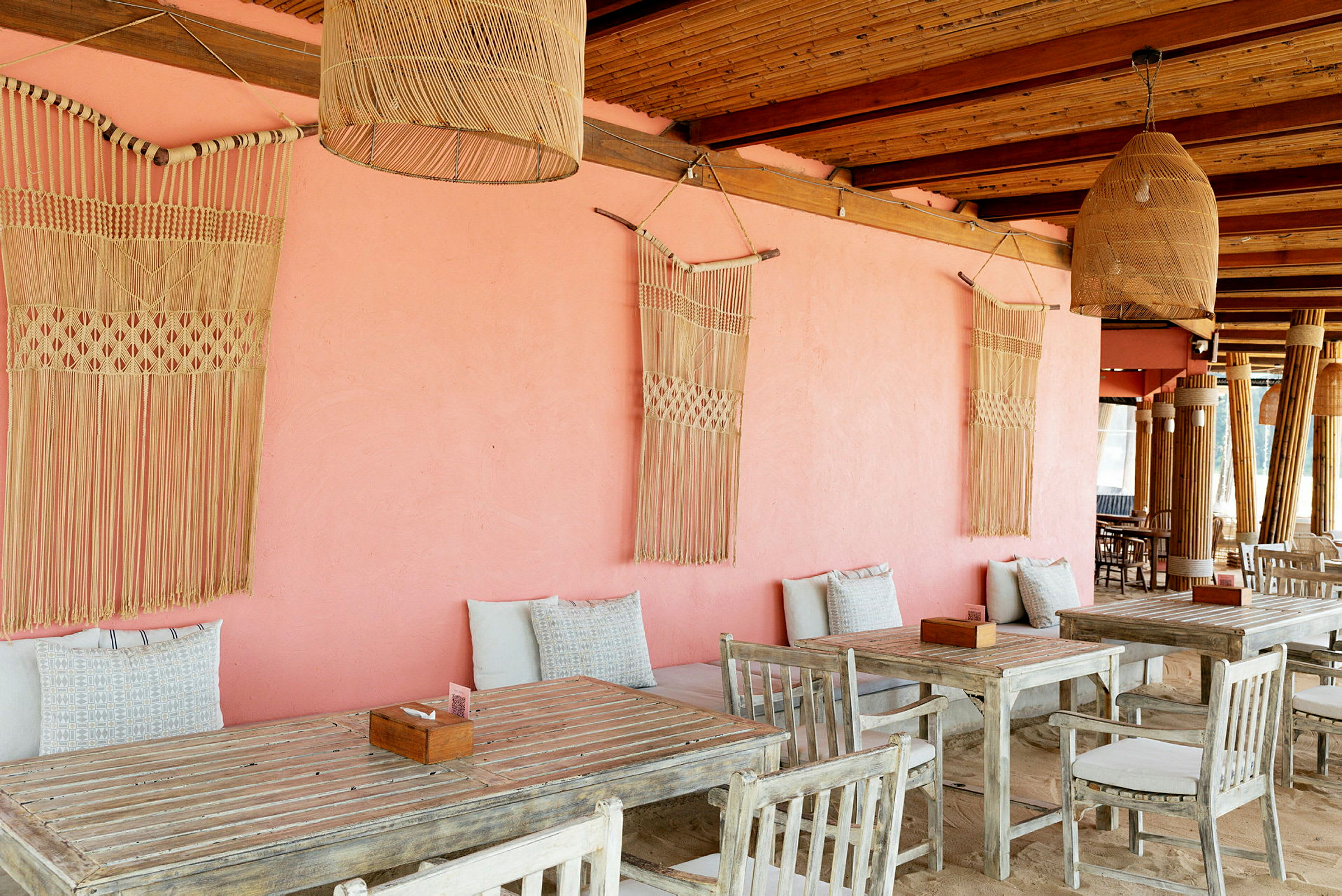 Rustik udendørs terrasse med borde og stole samt rosa væg med dekorative detaljer. (AI-genereret tekst)