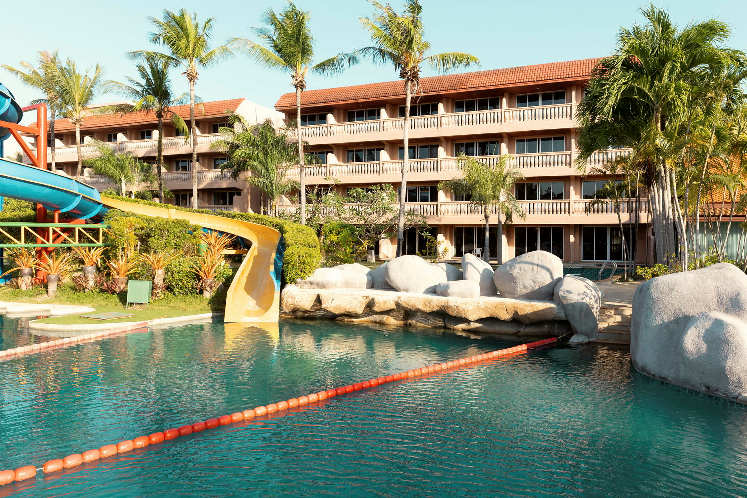 Pool med vandrutsjebane nær hotel med flere etager. (AI-genereret tekst)