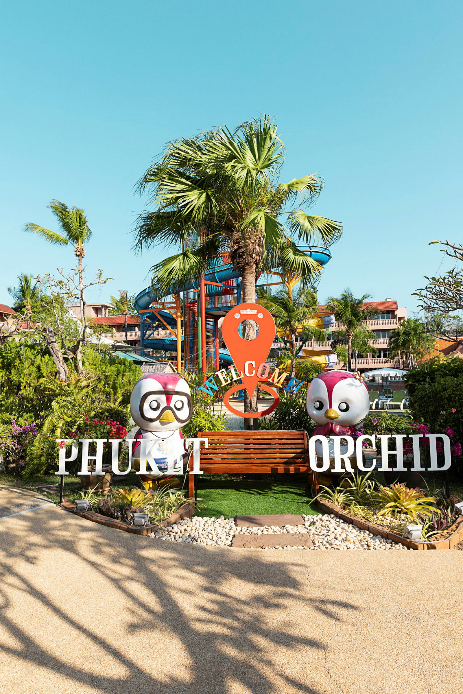 Indgang til Phuket Orchid med palmer i baggrunden. (AI-genereret tekst)